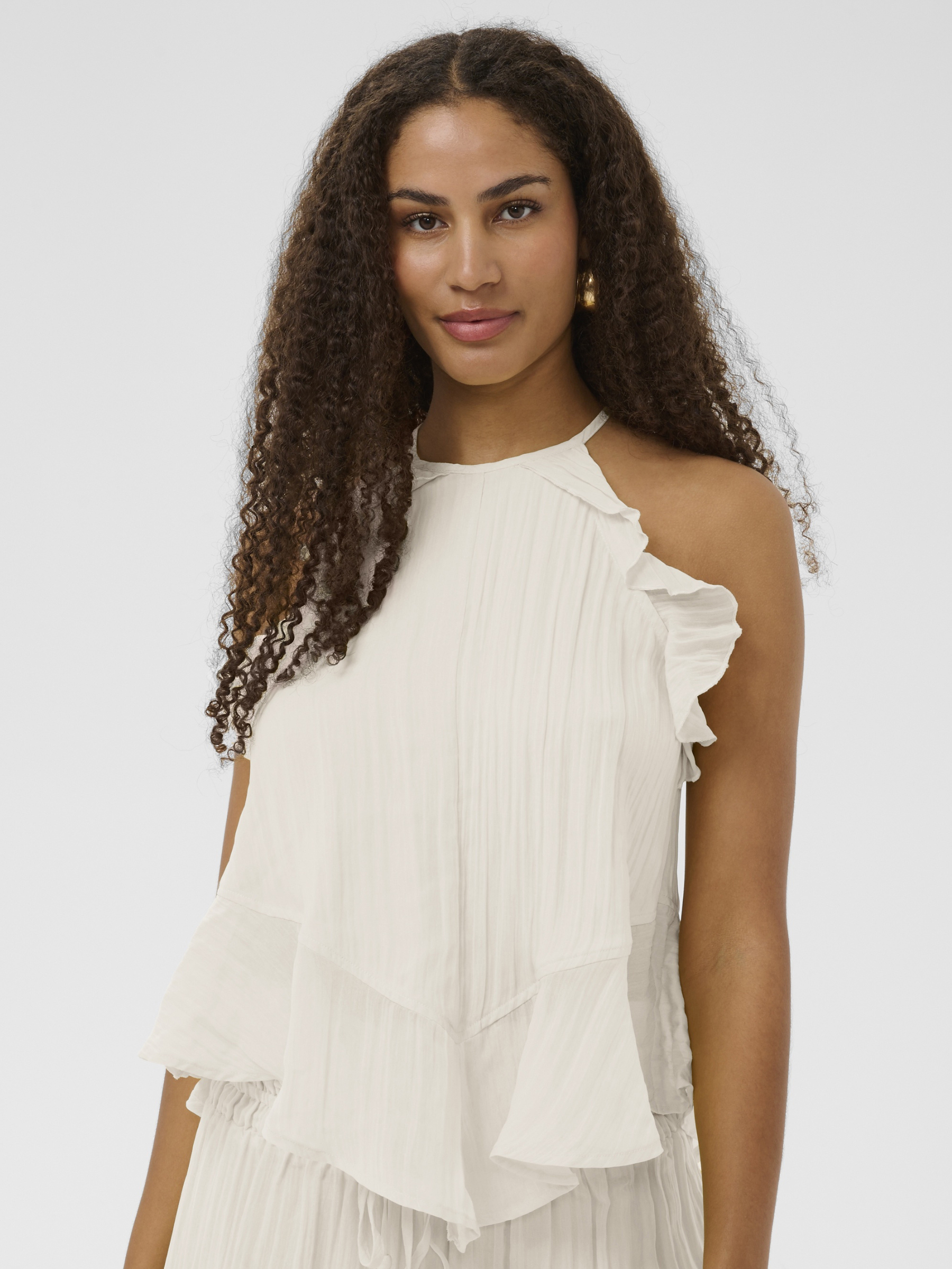 Cream Isabelle Top with pleated fabric, ruffle shoulder detail and peplum silhouette.