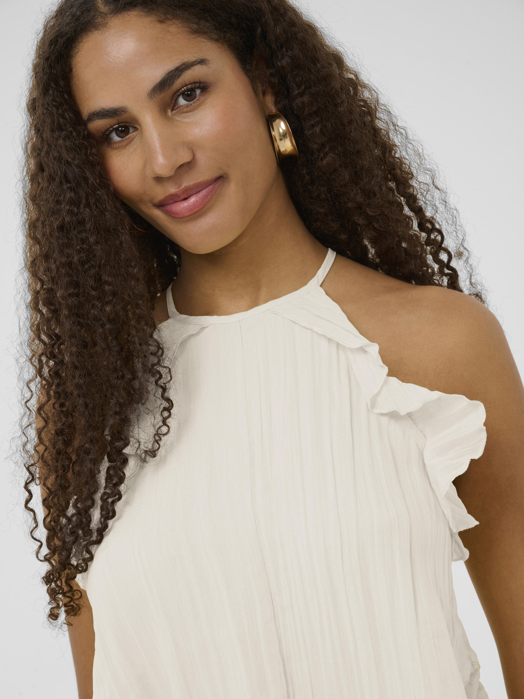 Cream Isabelle Top with pleated fabric, ruffle shoulder detail and peplum silhouette.