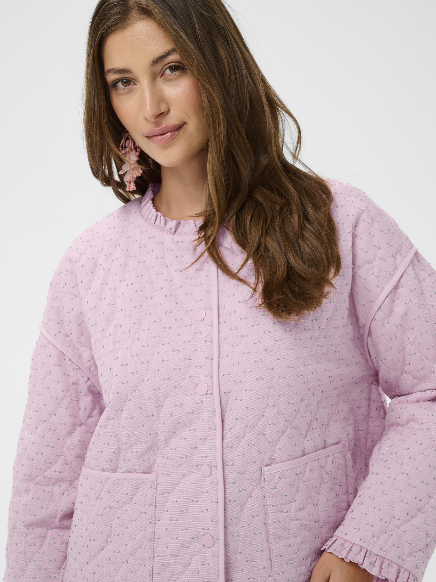 Cream Lummi quilted cotton jacket with round neckline, ruffle trim and button front in lightweight textured fabric.