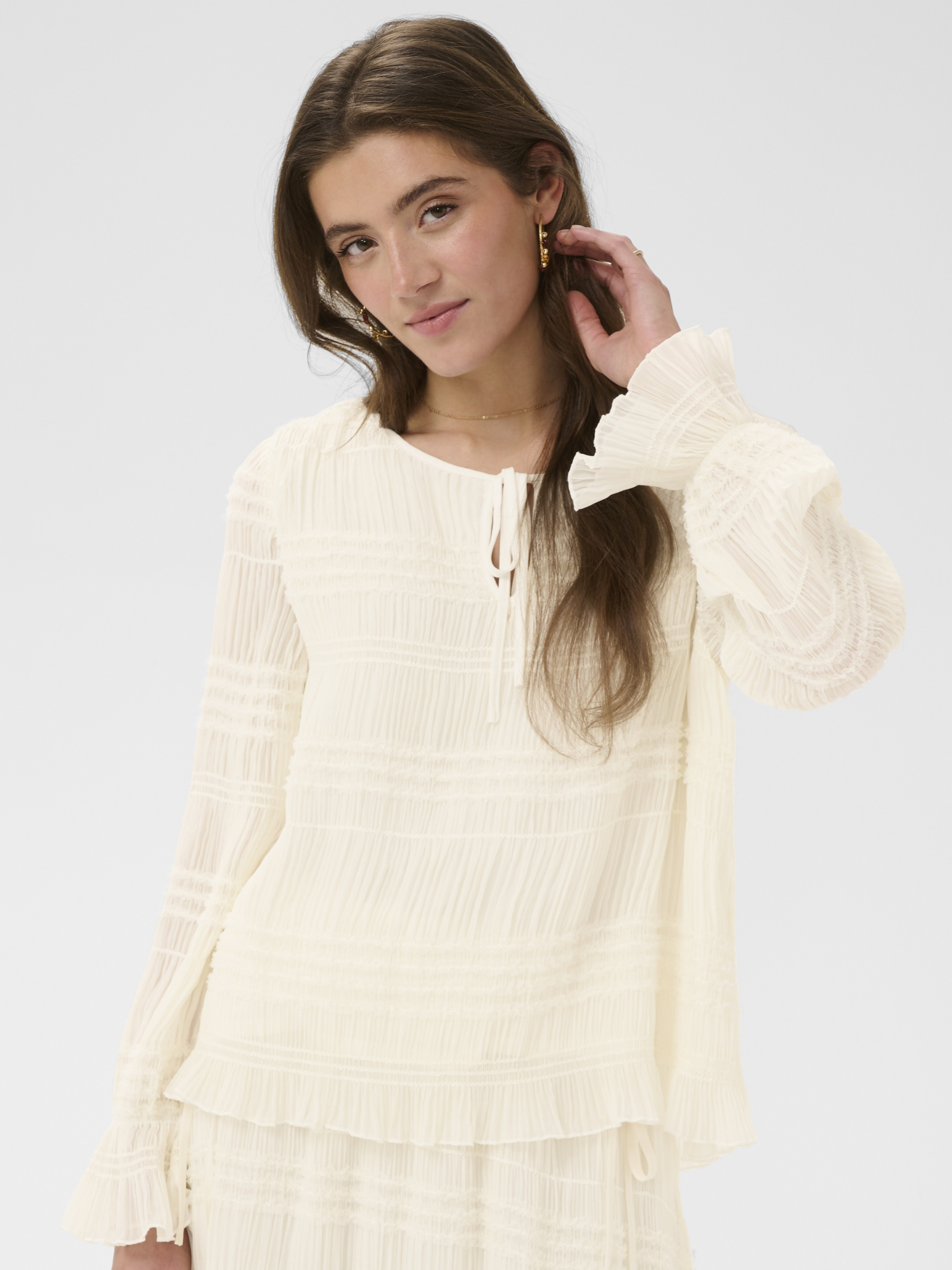 Cream Sissel Blouse with pleated texture, tie neckline and long fluted sleeves in a regular fit.
