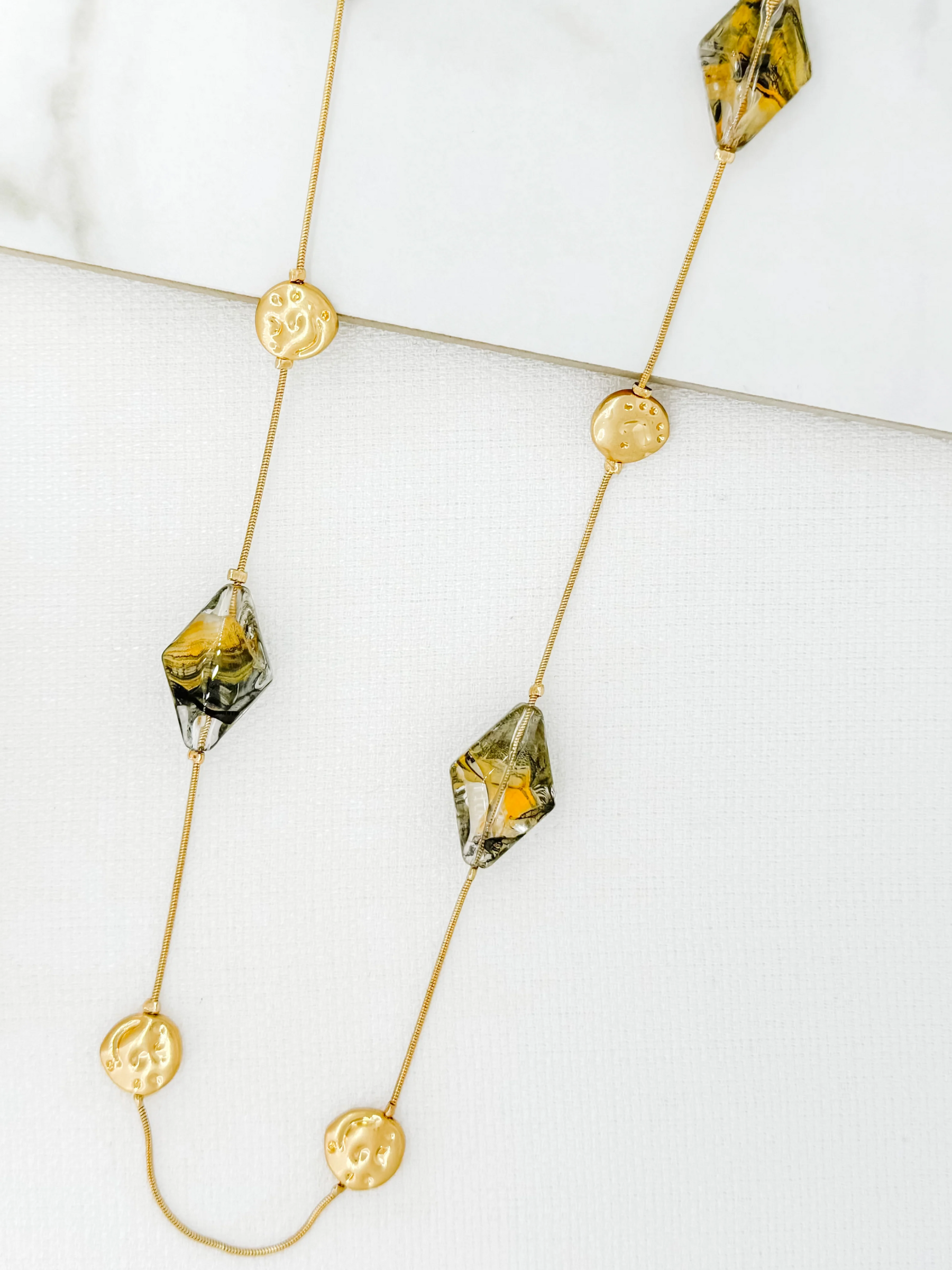 ENVY 4513 Necklace featuring a longline gold-effect chain with marbled geometric bead embellishments and textured gold discs, a bold women’s statement necklace for versatile styling.