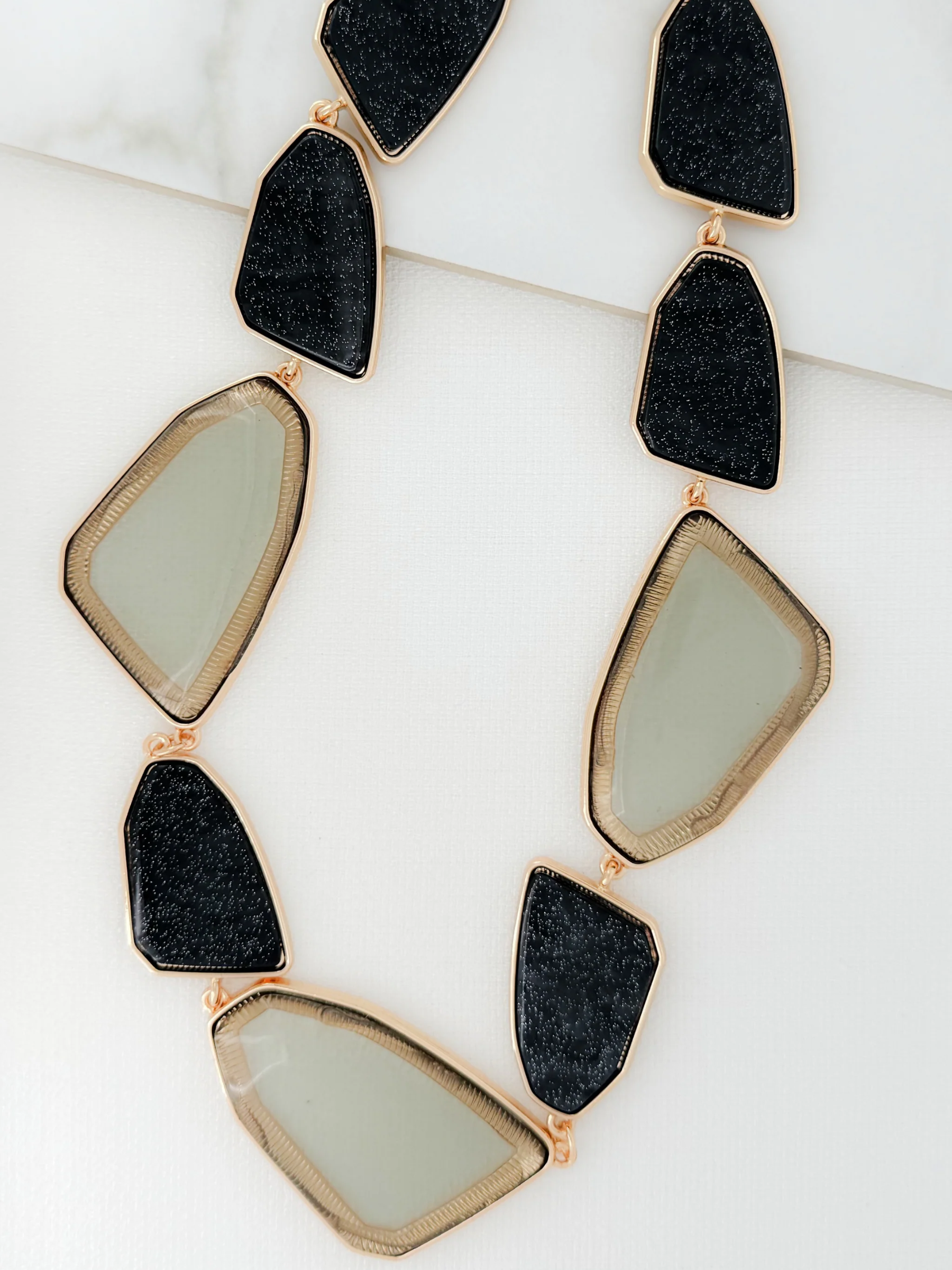 ENVY 4607 Necklace featuring alternating black-effect and neutral-effect geometric stones framed in gold-effect detail, designed as a bold statement necklace for versatile styling.
