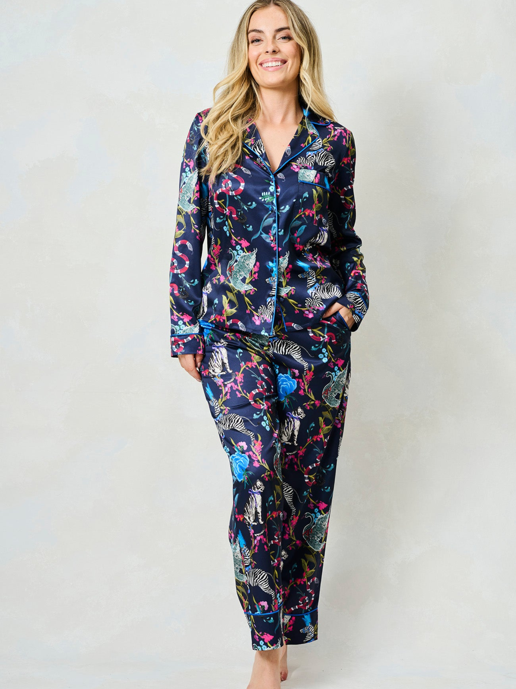 Hope & Ivy SUZANNE Zebra Pyjamas – women’s satin pyjama set featuring hand-painted zebra and floral print, blue piping, button-up shirt and matching trousers. Ideal for lounging, gifting or travel.