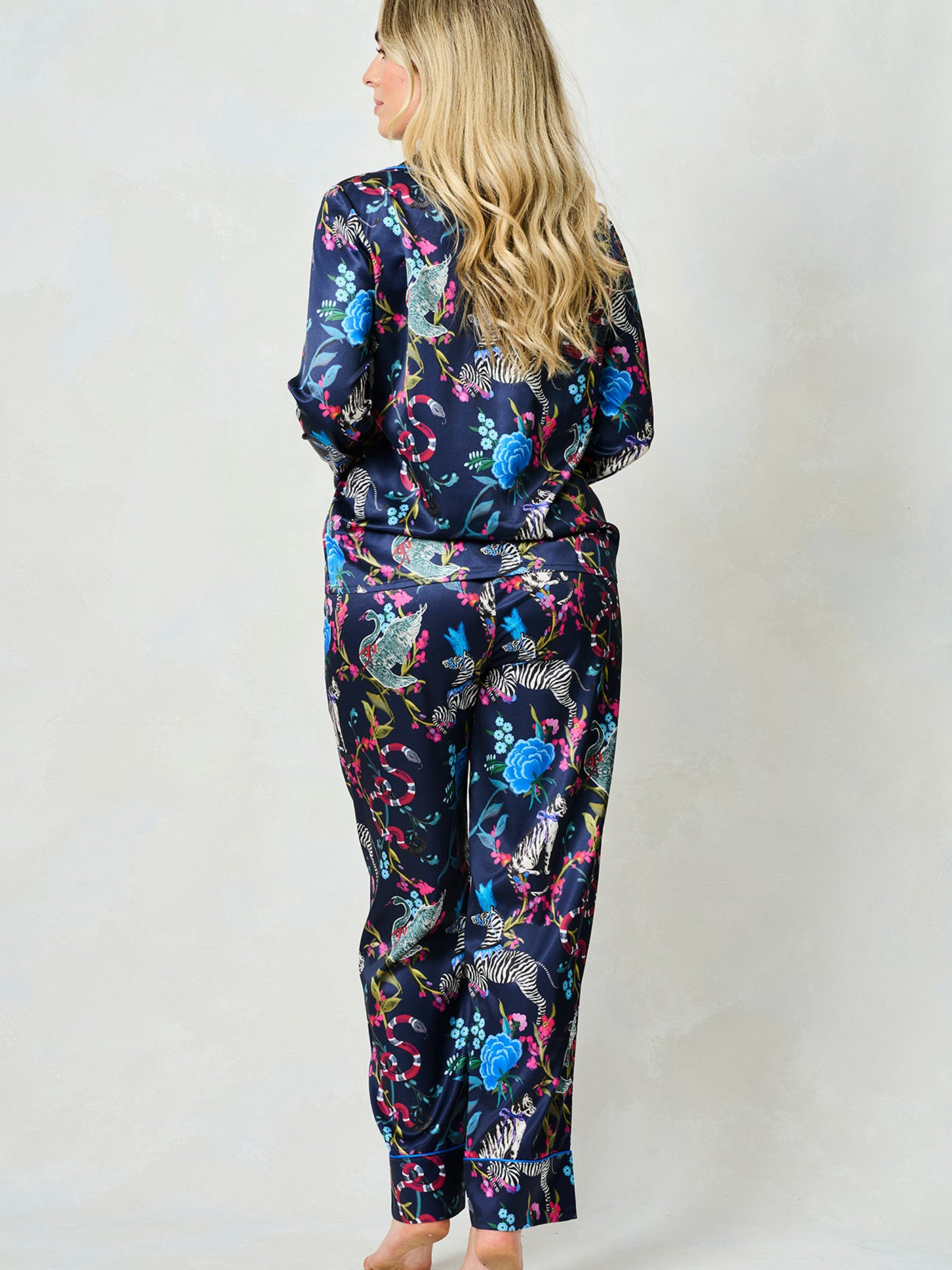 Hope & Ivy SUZANNE Zebra Pyjamas – women’s satin pyjama set featuring hand-painted zebra and floral print, blue piping, button-up shirt and matching trousers. Ideal for lounging, gifting or travel.
