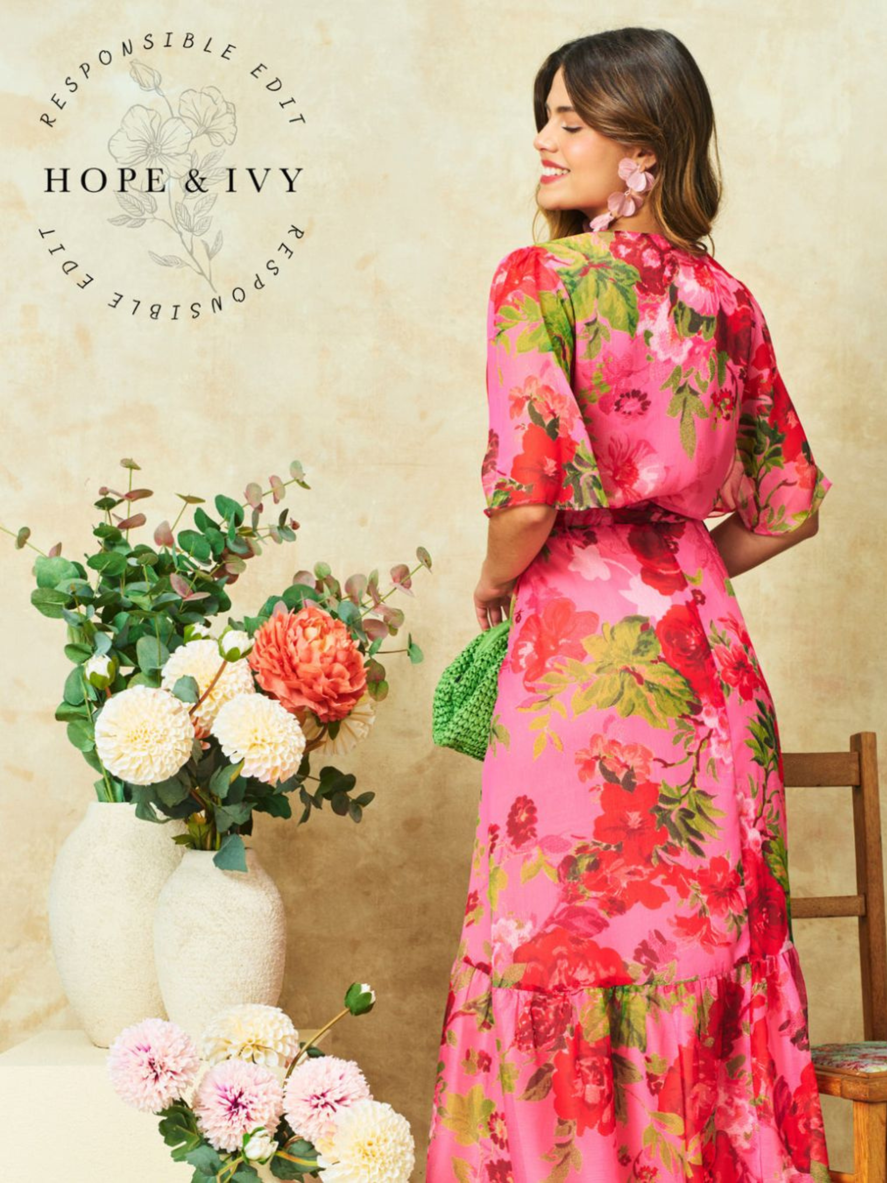 Hope & Ivy Roxanne Floral Dress – sustainable pink floral maxi wrap dress with flutter sleeves and tie waist. Hand-painted red floral design made from 100% recycled materials. Perfect for weddings and summer occasions.