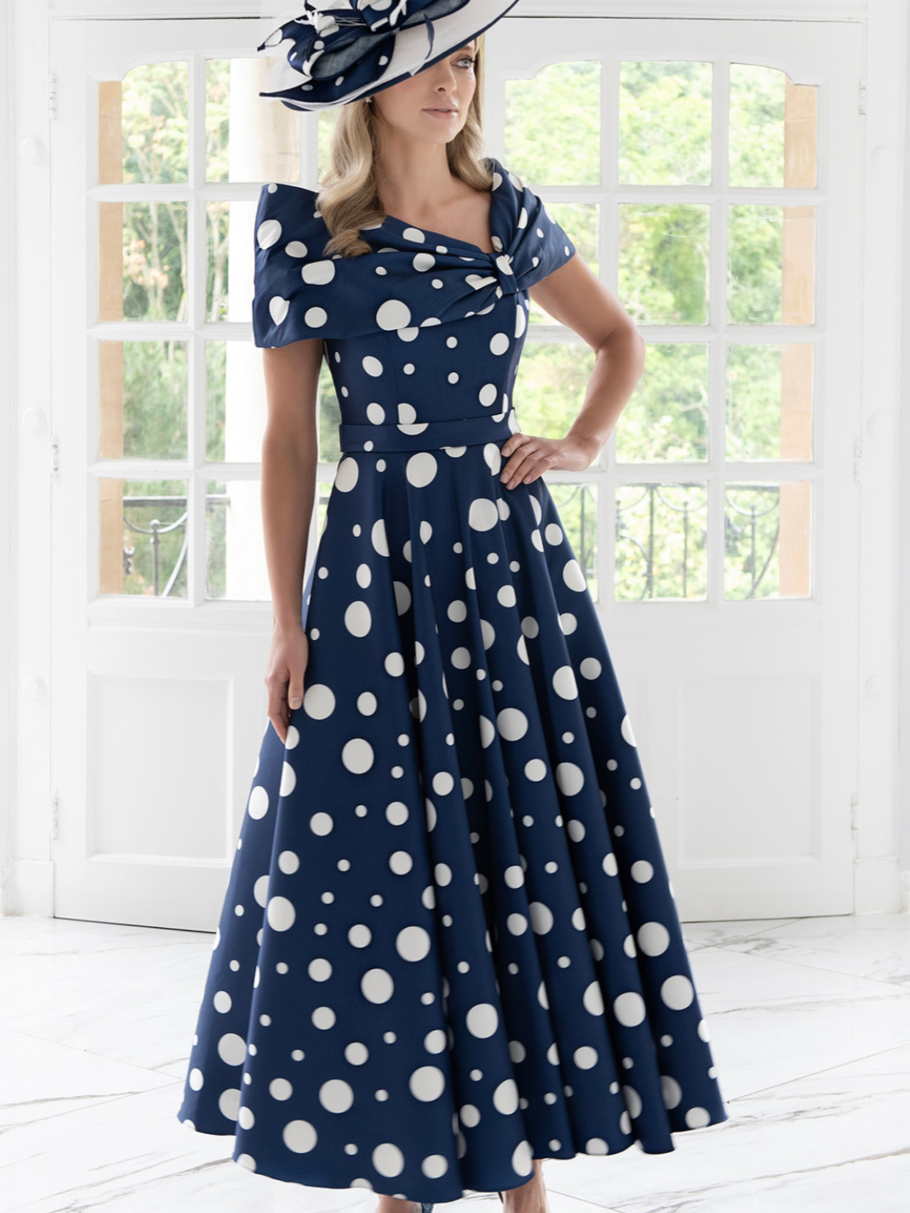 Irresistible IR8821TJ Navy/Ivory Dress with off-the-shoulder pleated collar, fitted waist and full A-line polka-dot skirt - a timeless occasion dress perfect for weddings and elegant events.