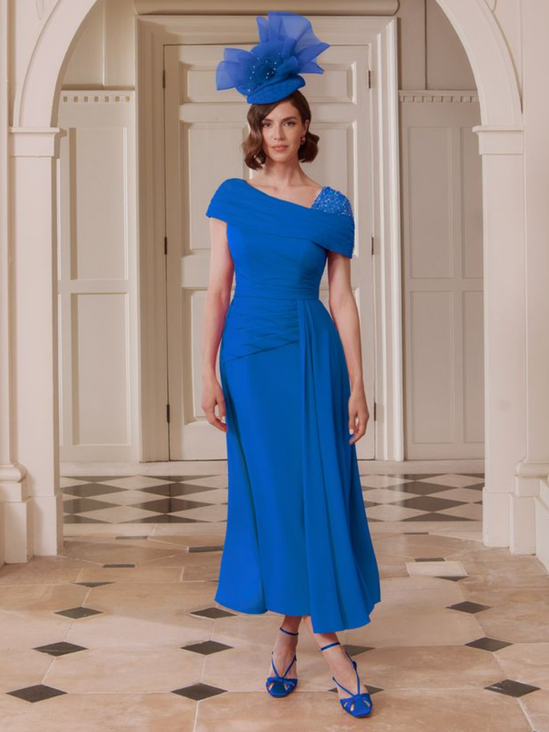 John Charles 29346B Sapphire Dress with asymmetric neckline, beaded shoulder detail, ruched bodice and flowing A-line midi skirt — a sophisticated sapphire occasion dress perfect for weddings and elegant events.