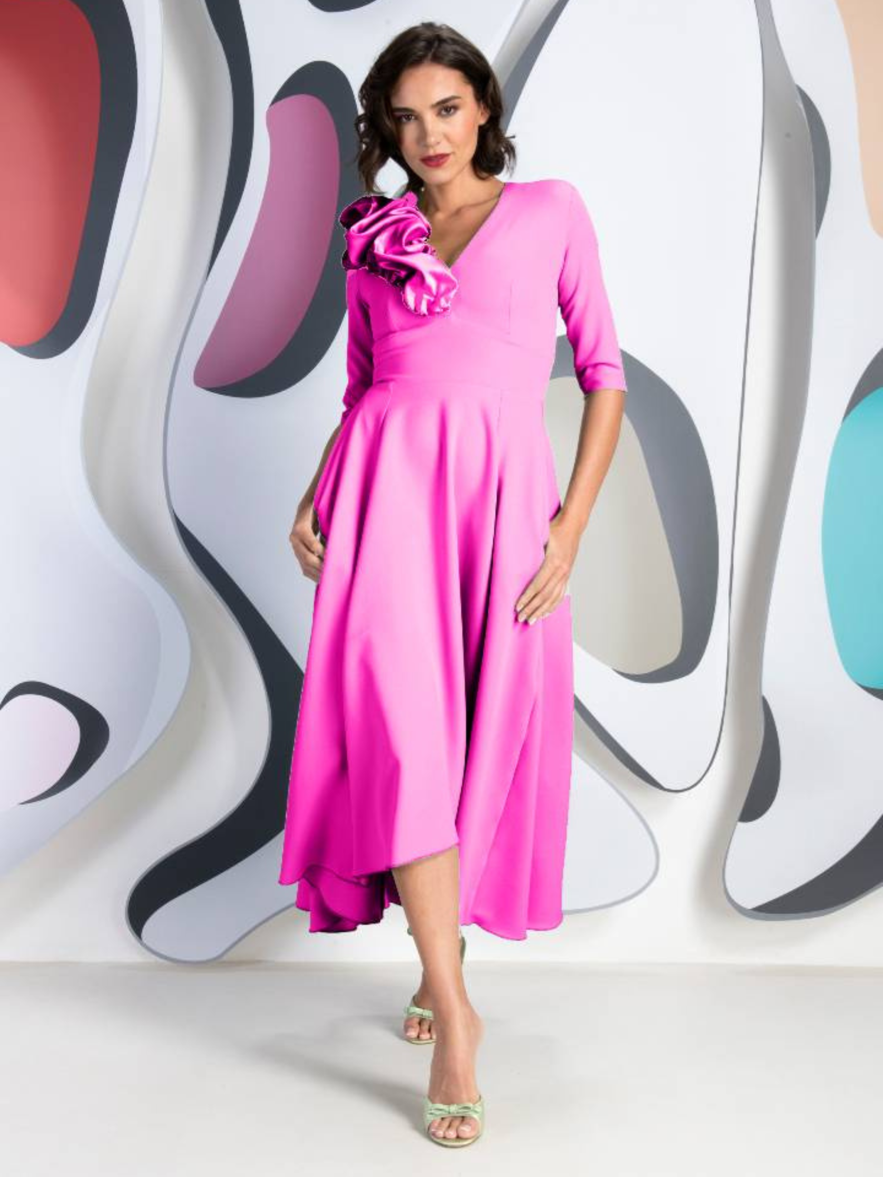 Kevan Jon Betty B Bright Pink Knee Dress in Delauney Duchess fabric with a V-neckline, sculptural shoulder ruffle and flowing high-low flared skirt.