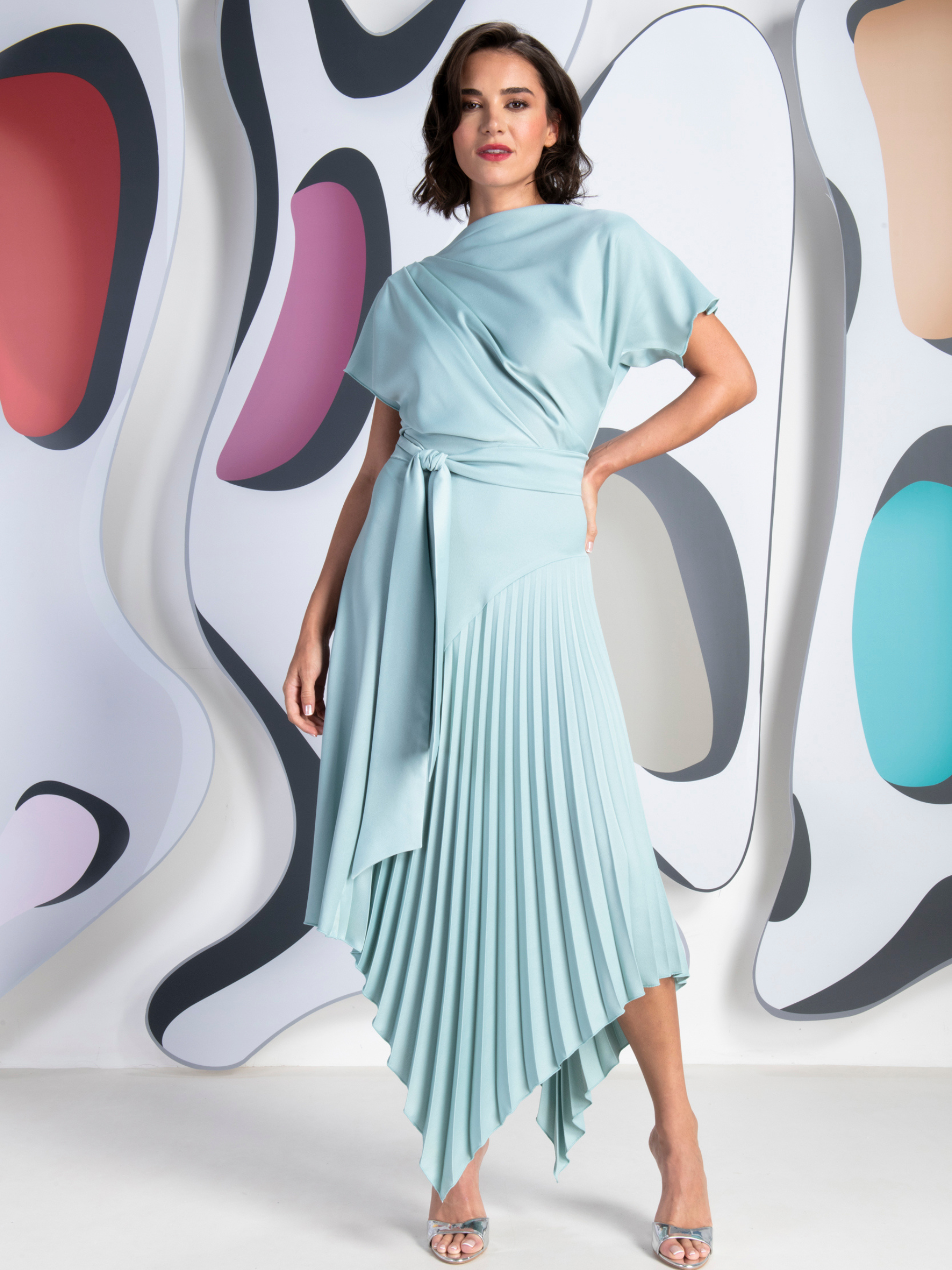 Kevan Jon Mila Pleat Dusty Blue Knee Dress in satin crepe with draped bodice, tie waist and asymmetric pleated skirt.