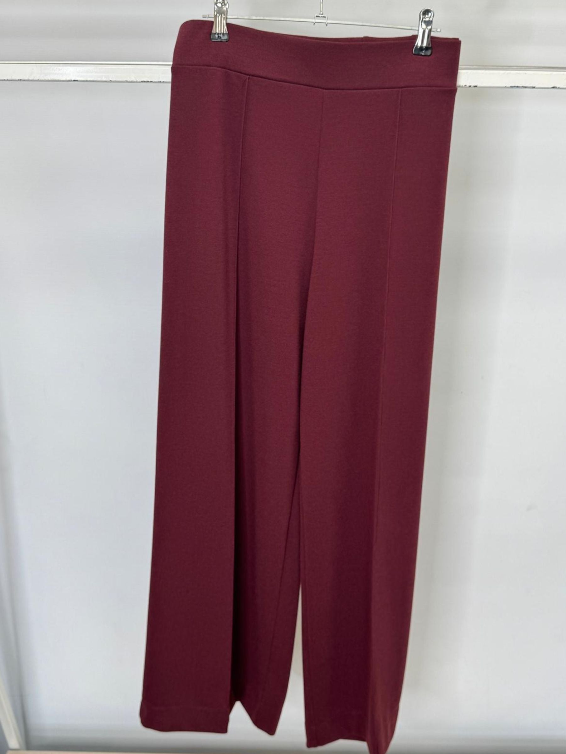 Maroon pants hanging on a white background