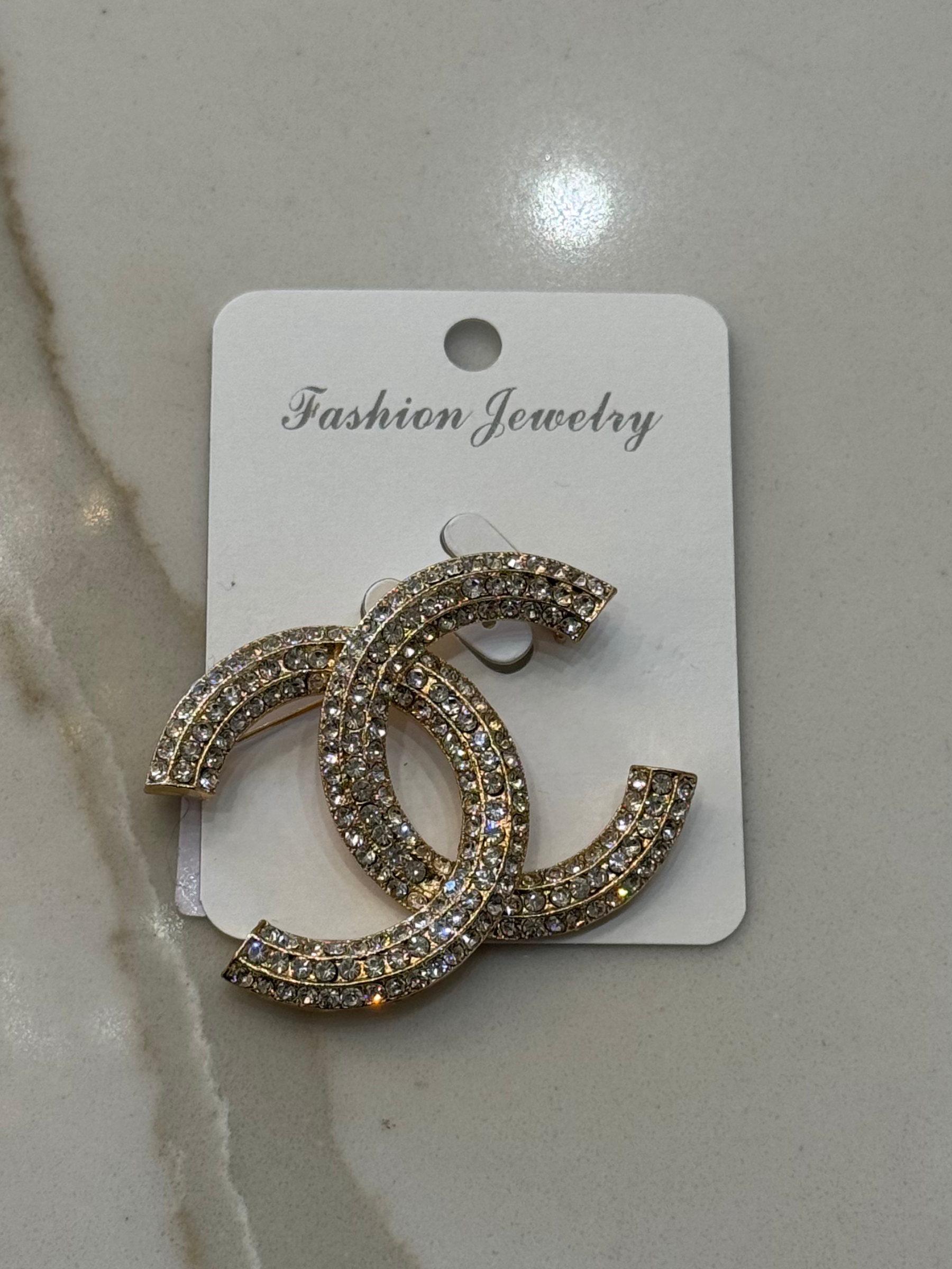 Nouvelle CC Brooch Gold – luxury women’s crystal brooch with double C design, gold-tone finish and sparkling rhinestones. Perfect statement accessory for blazers, scarves and evening wear.