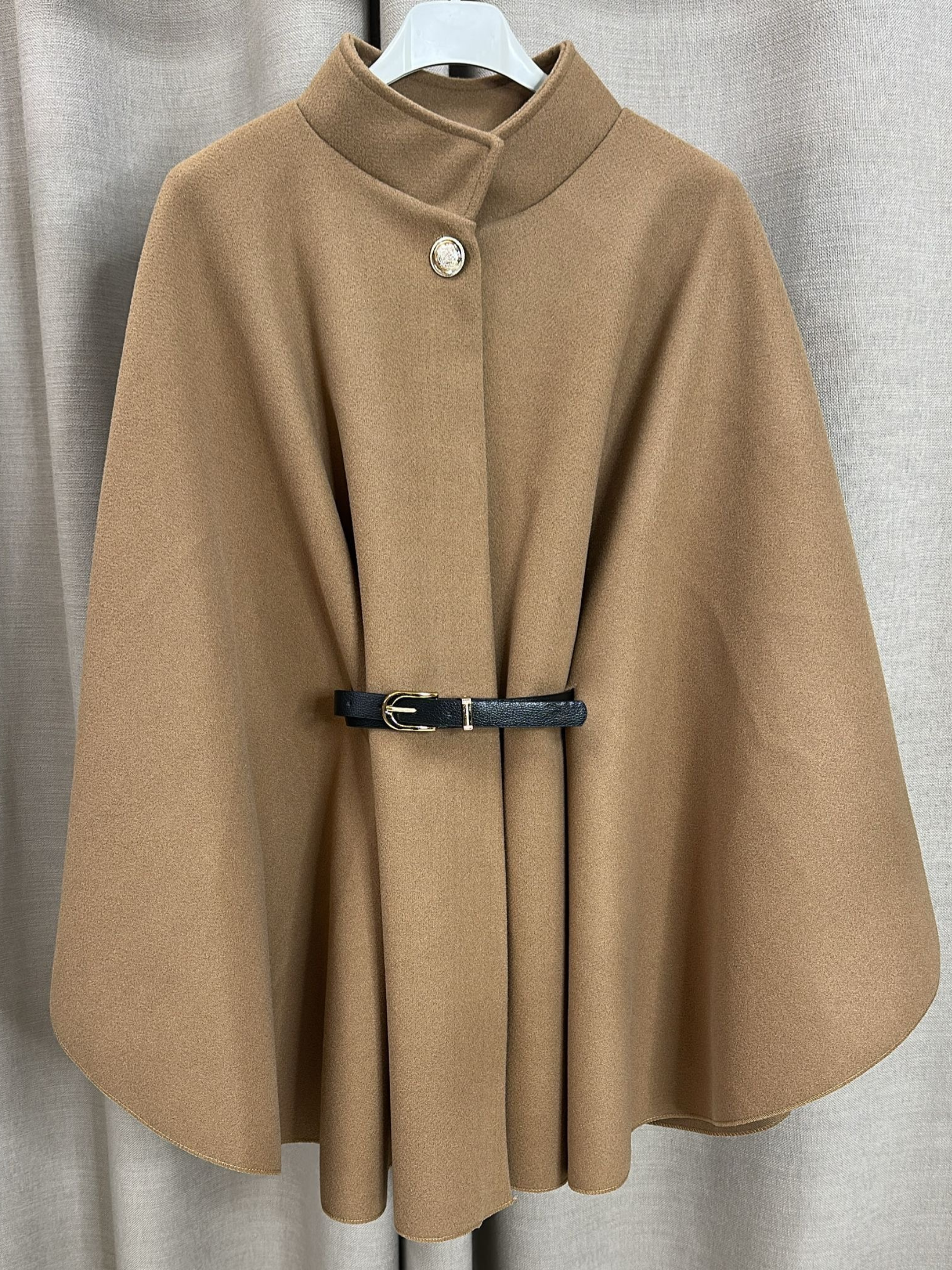 The QBAW25 RR Camel Carrie Cape features a structured silhouette with wide sleeves, a high neckline and elegant gold button detailing. Finished with a detachable belt for a flattering fit, this chic cape blends timeless tailoring with modern sophistication - perfect for layering over seasonal outfits.