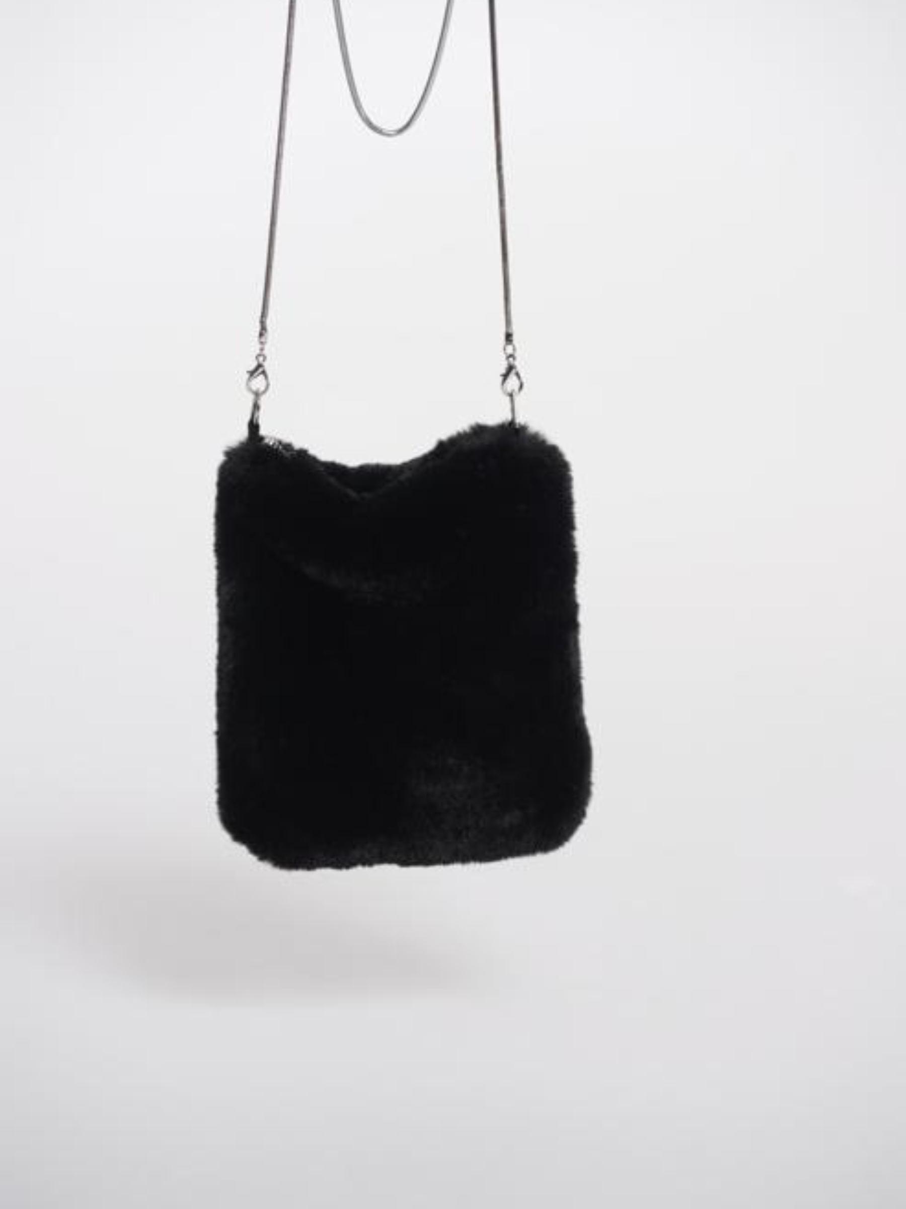 Women’s black faux fur crossbody bag with slim chain strap – soft plush evening bag perfect for winter outfits and chic day-to-night styling.