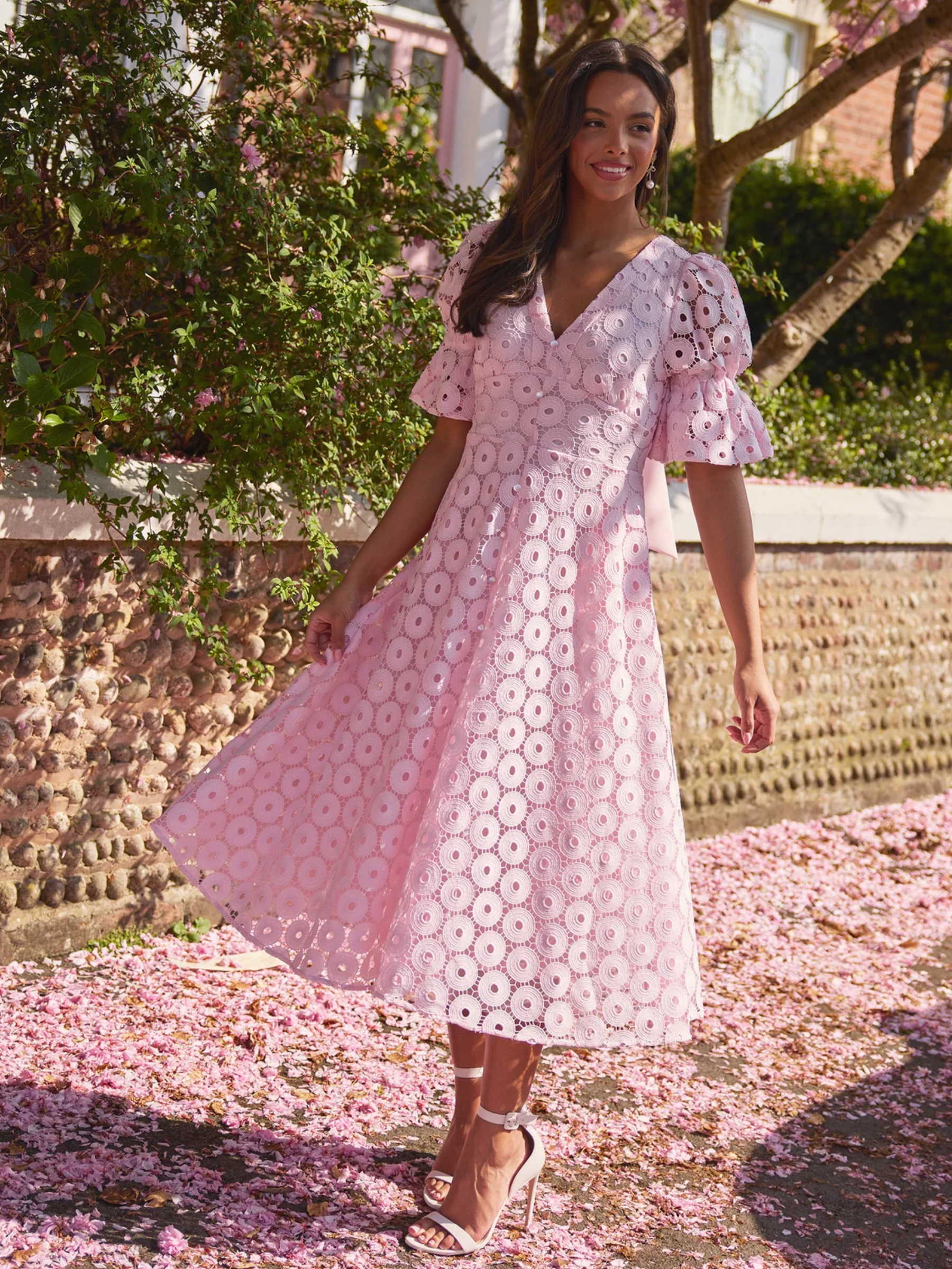 Pale pink skater midi dress with broderie-style fabric, puff sleeves and bow back detail.