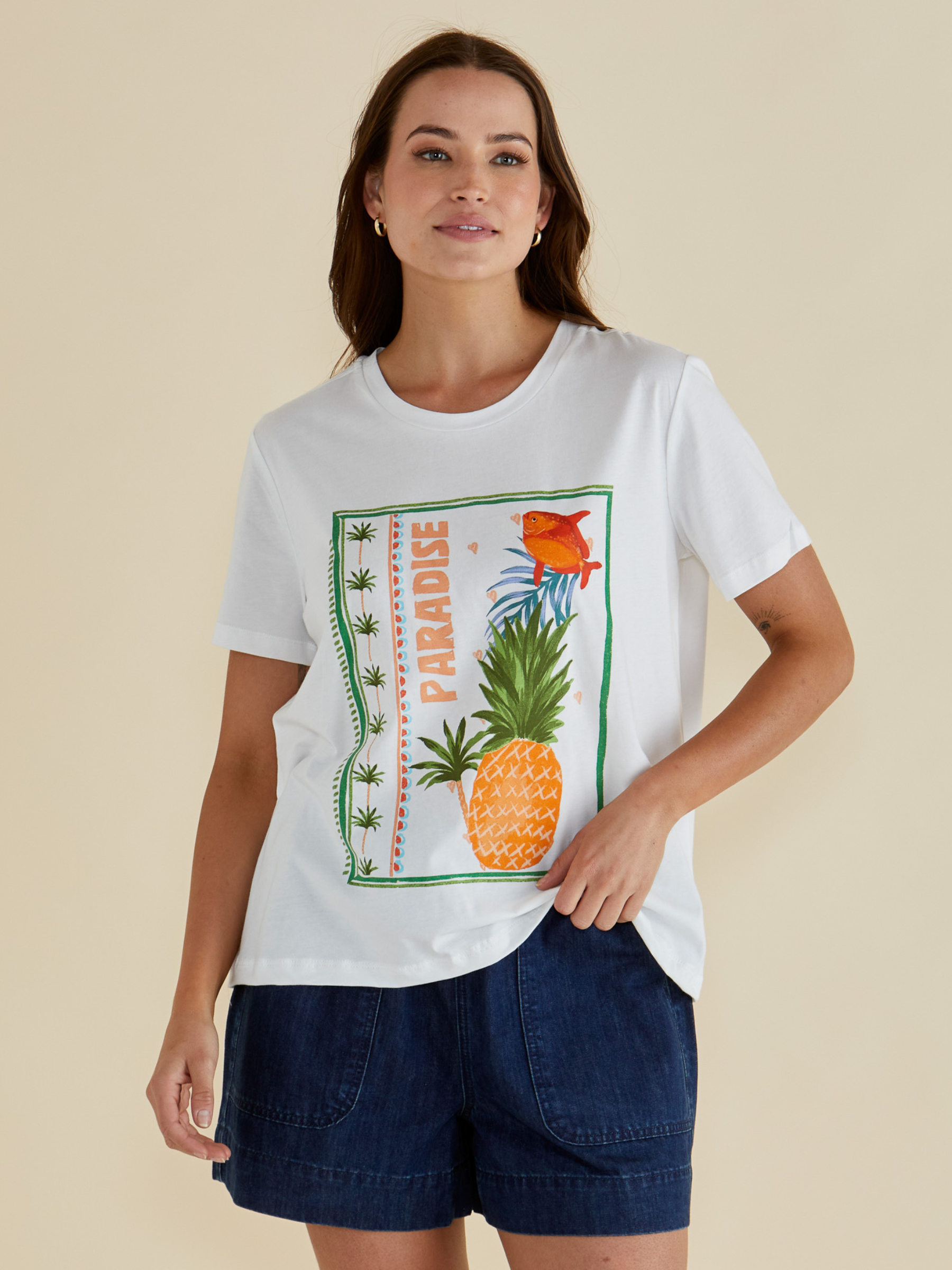 Betty Ellia Crew Tee with crew neckline, short sleeves and statement front graphic design available in tropical “Paradise” print or pink striped fish motif.