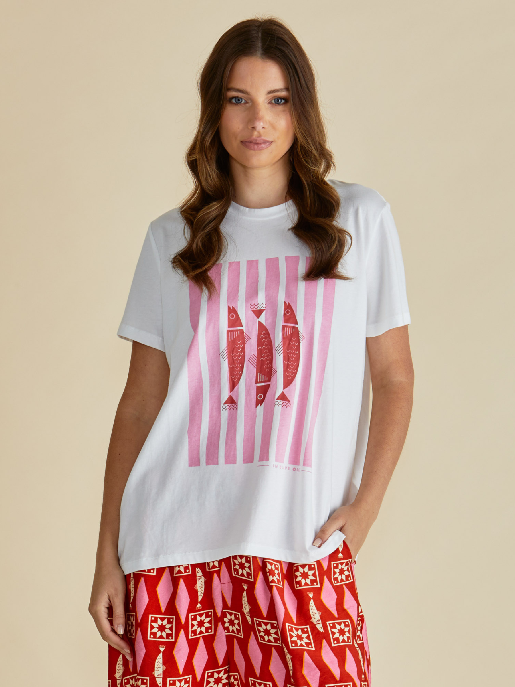Betty Ellia Crew Tee with crew neckline, short sleeves and statement front graphic design available in tropical “Paradise” print or pink striped fish motif.
