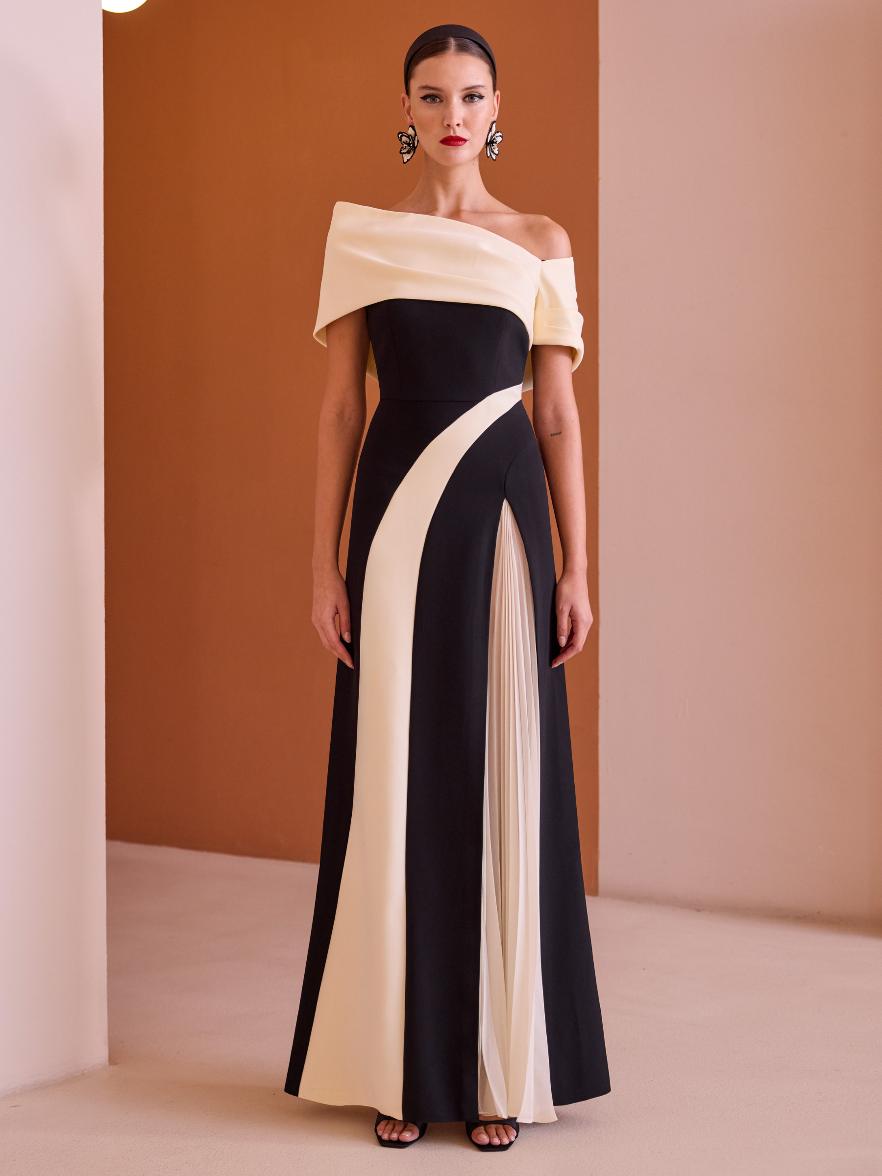 Carla Ruiz 52546 Black Dress with asymmetric off-shoulder neckline, monochrome sculpted panels and flowing A-line skirt with pleated detail.