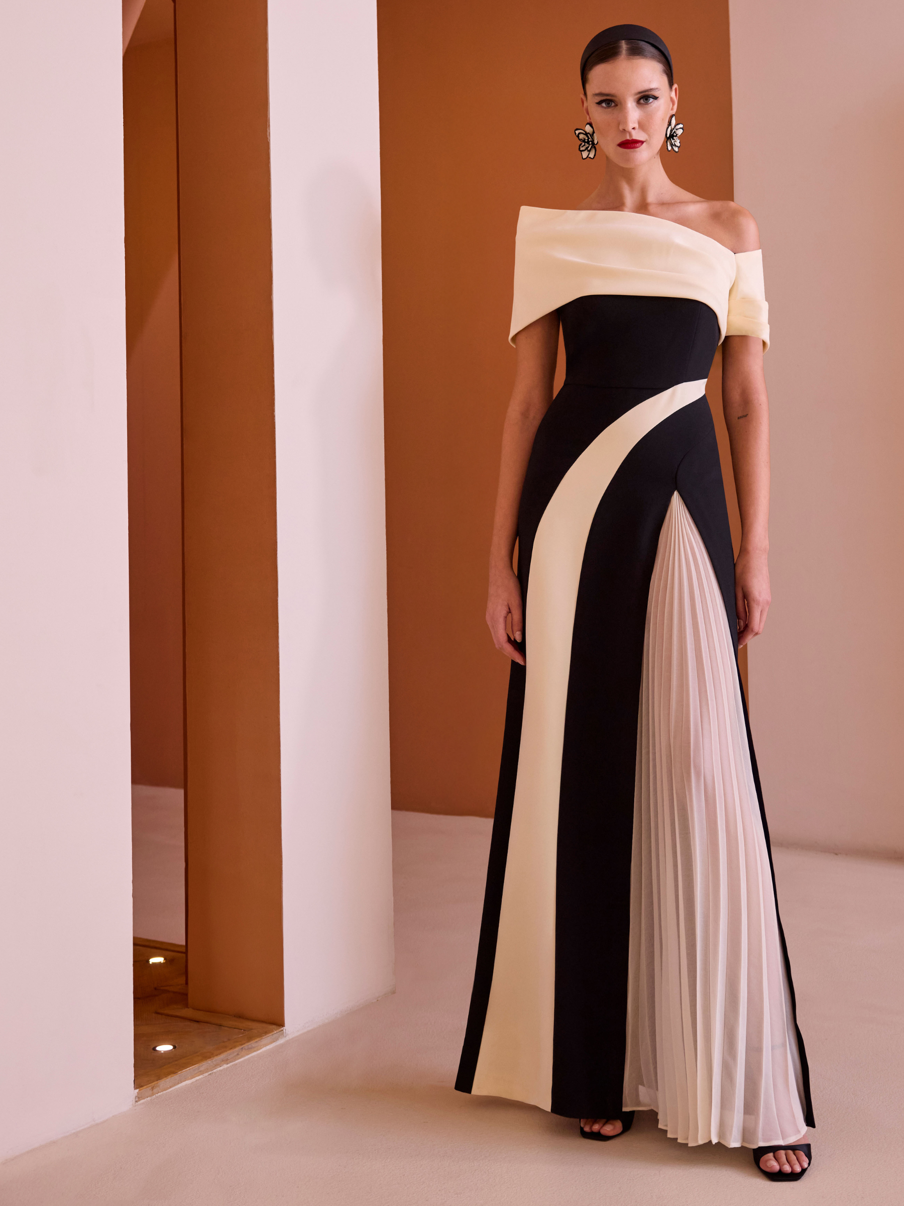 Carla Ruiz 52546 Black Dress with asymmetric off-shoulder neckline, monochrome sculpted panels and flowing A-line skirt with pleated detail.