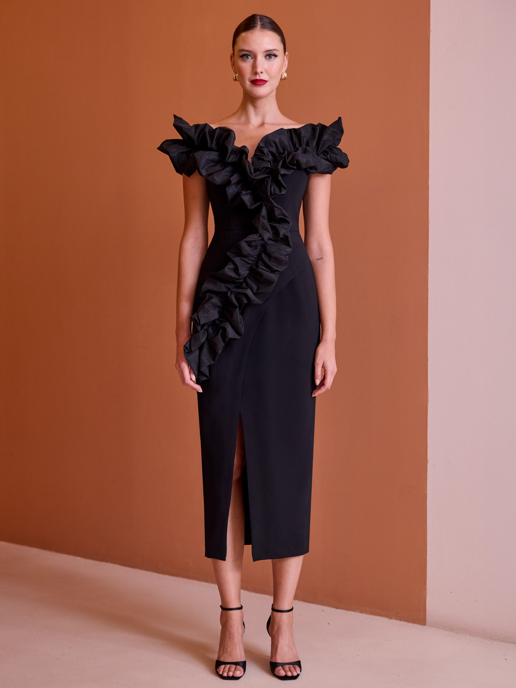 Carla Ruiz 52606 black fitted dress with off-the-shoulder neckline, ruffle detailing and front split.