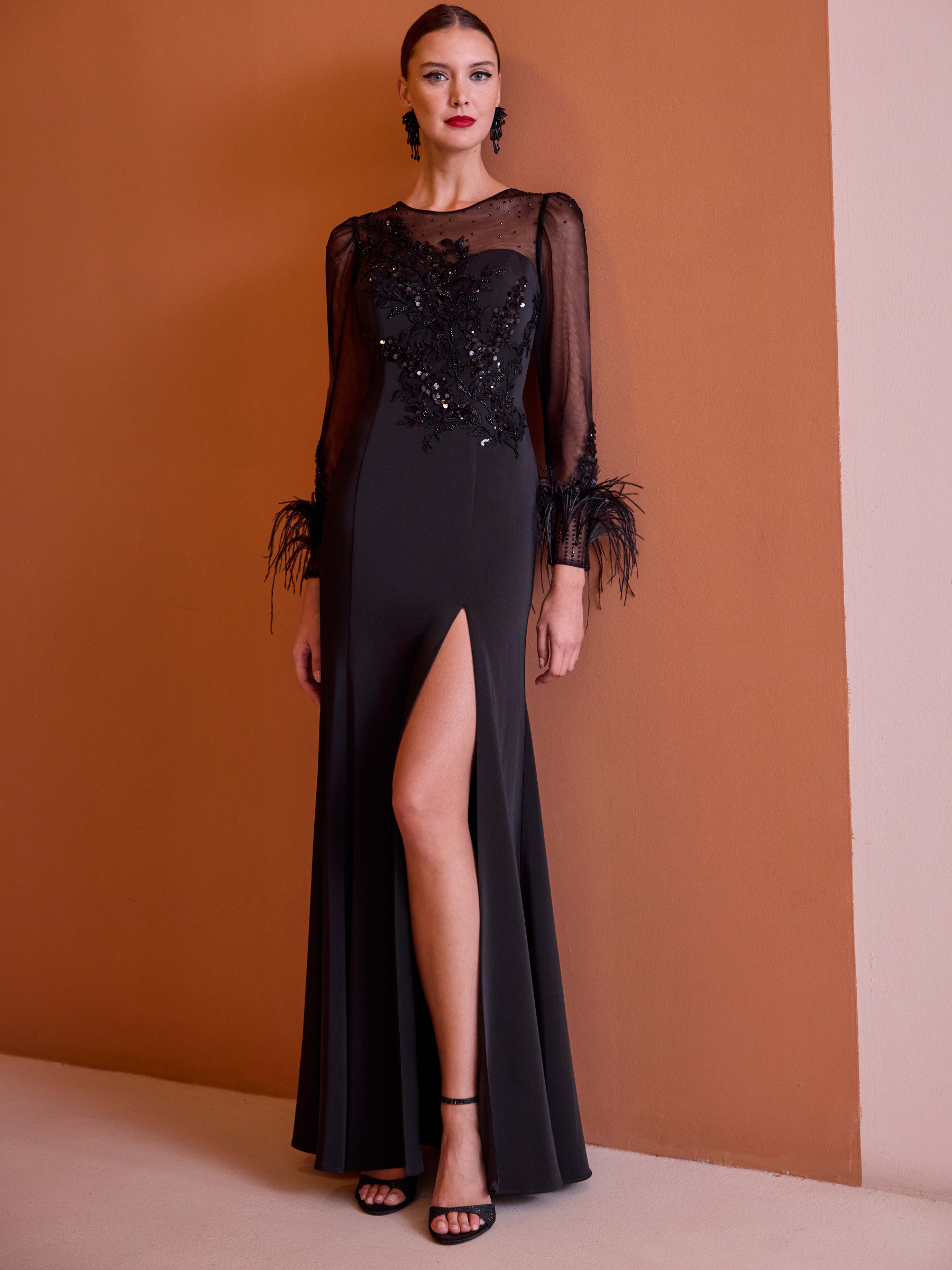 Carla Ruiz 52729 black dress with sheer embellished bodice, long sleeves, feather cuffs and front split.