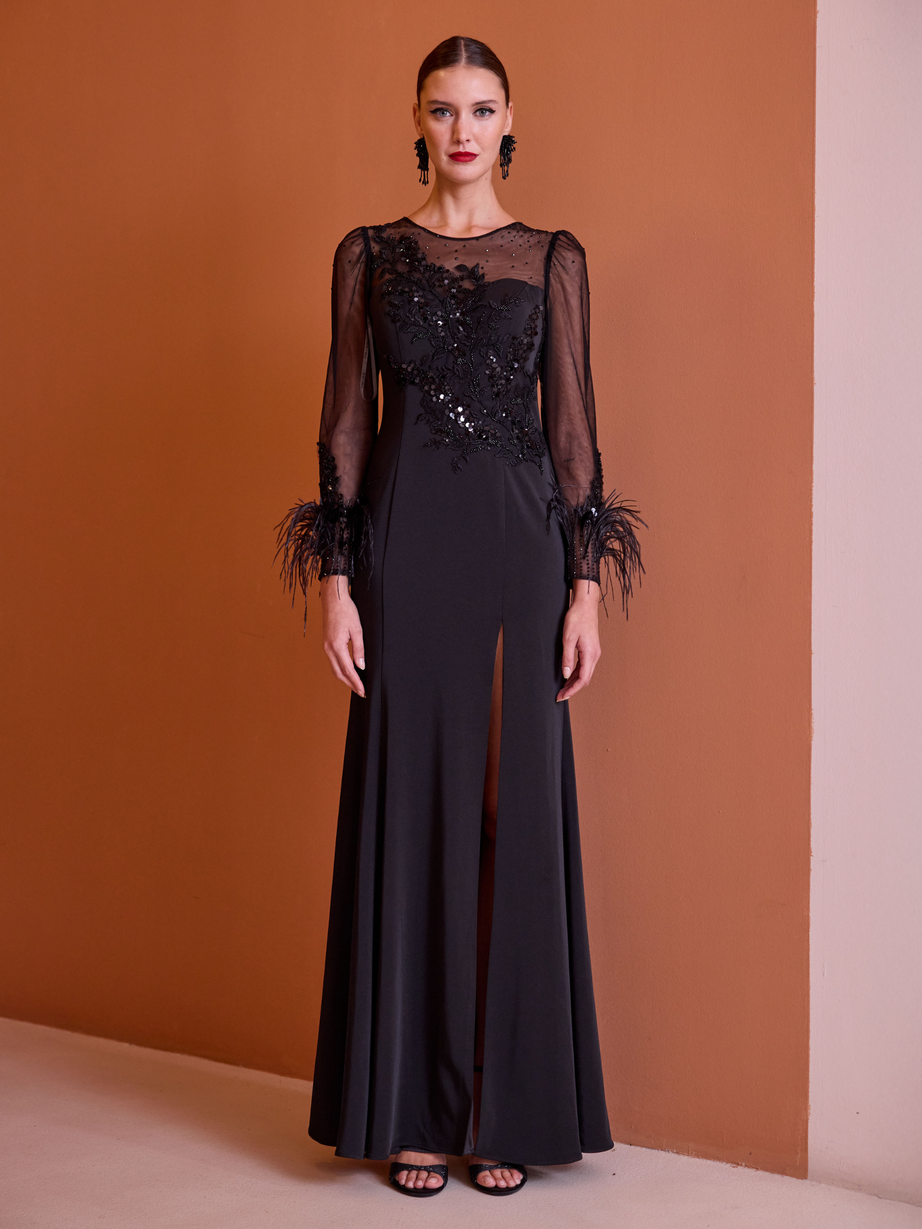 Carla Ruiz 52729 black dress with sheer embellished bodice, long sleeves, feather cuffs and front split.