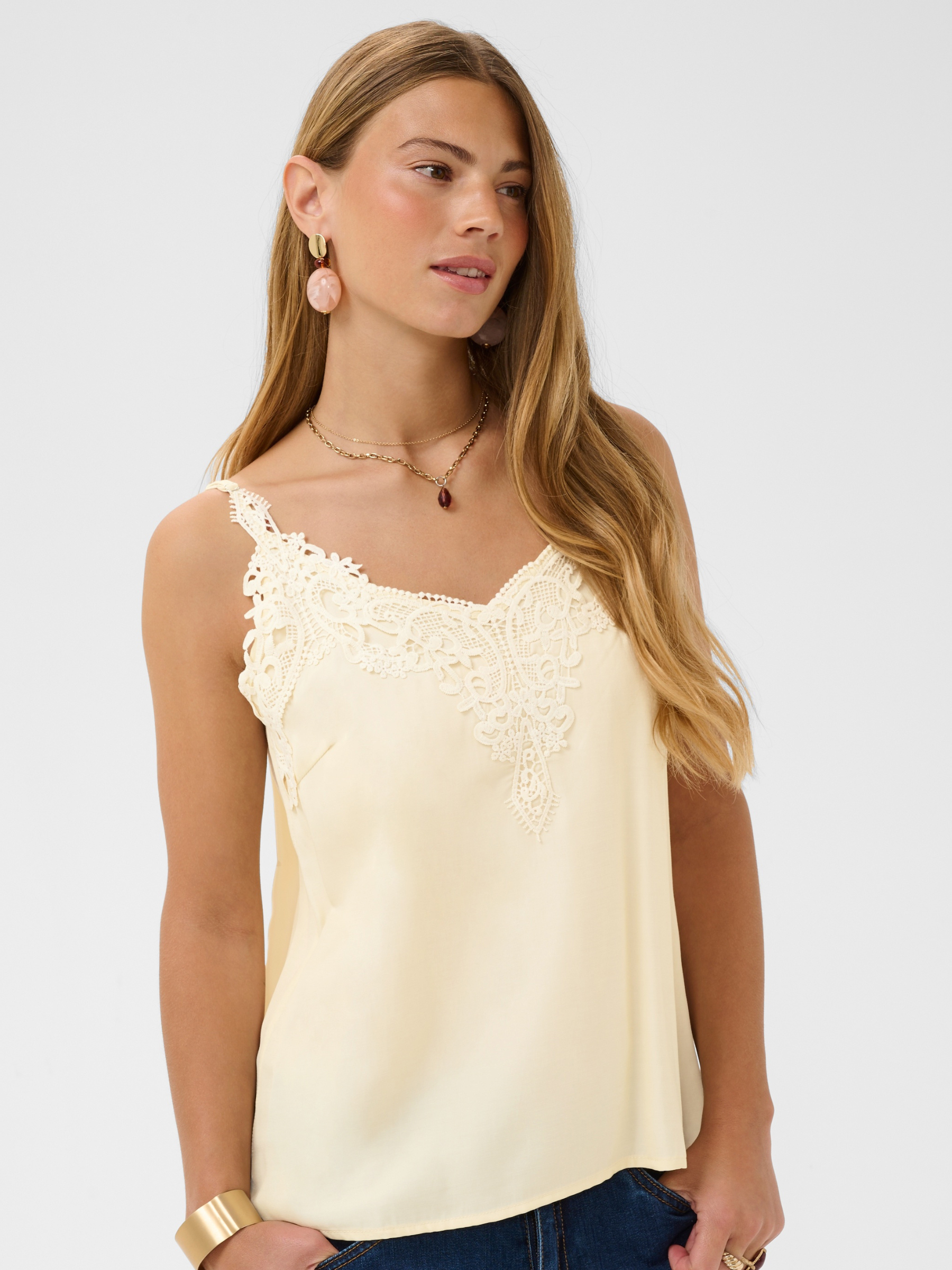 Cream Anna women’s A-line camisole top with lace neckline detail, adjustable straps and hip-length fit, styled with jeans.