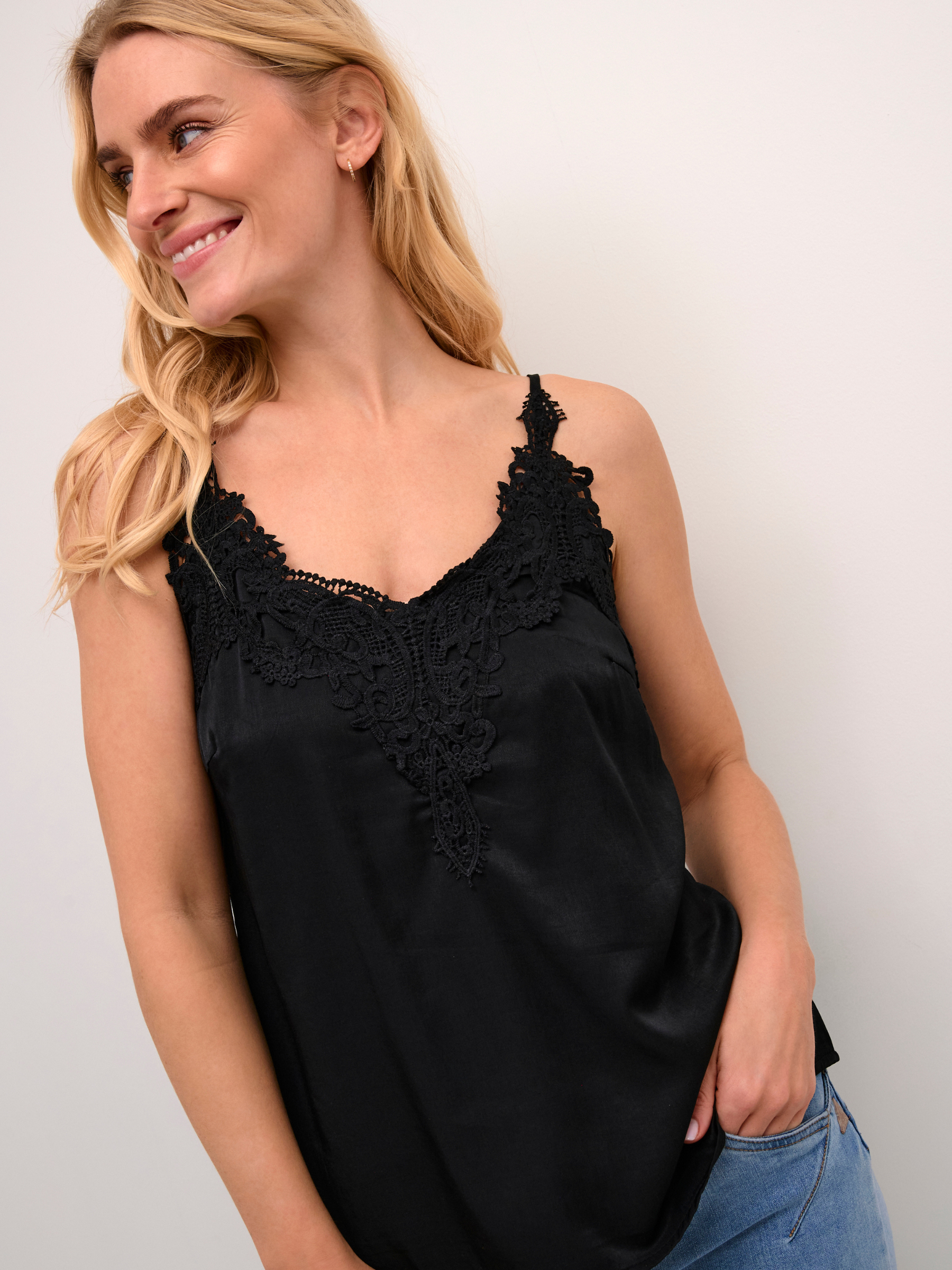 Cream Anna women’s A-line camisole top with lace neckline detail, adjustable straps and hip-length fit, styled with jeans.