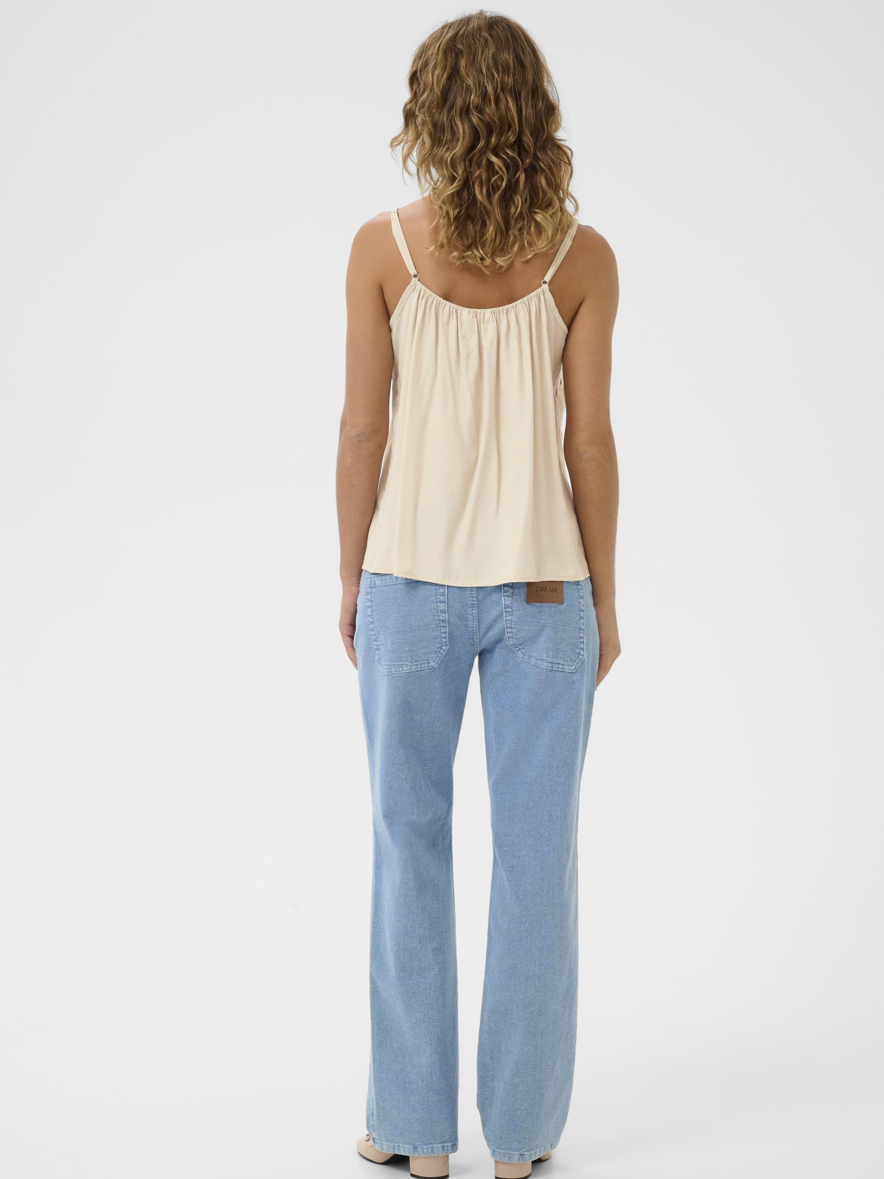 Cream Anna women’s A-line camisole top with lace neckline detail, adjustable straps and hip-length fit, styled with jeans.