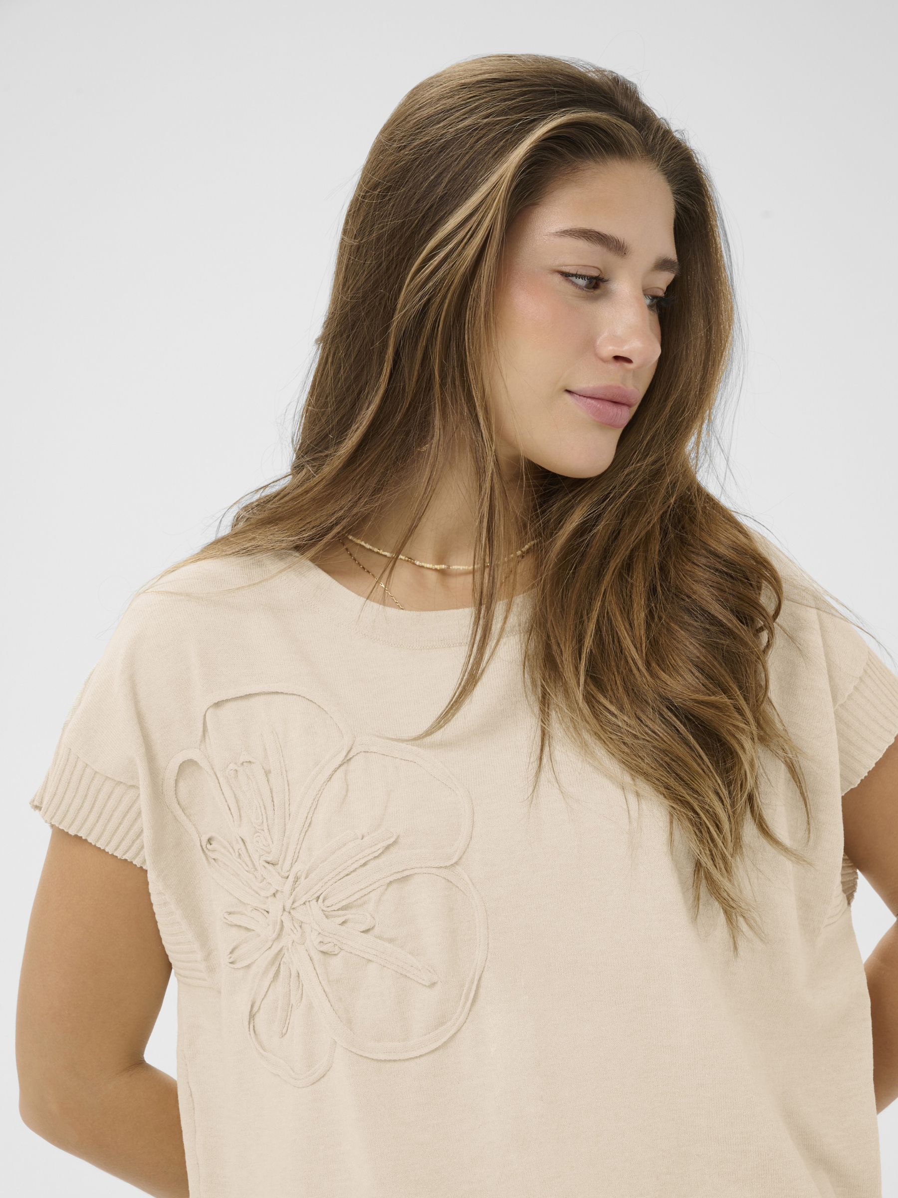 Cream Dela Knit With Deco Slipover lightweight knit top with floral applique detail and short sleeves.
