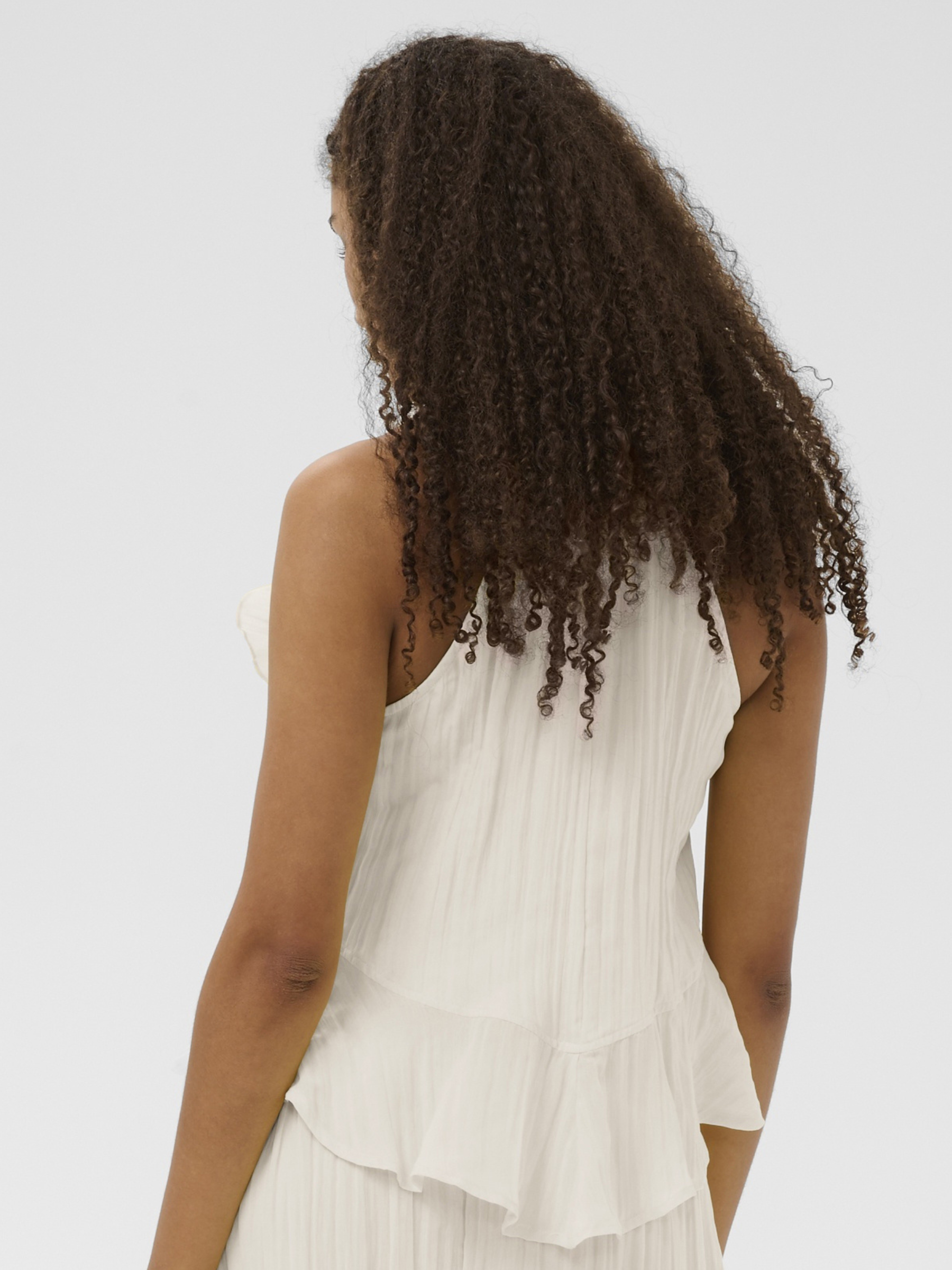 Cream Isabelle Top with pleated fabric, ruffle shoulder detail and peplum silhouette.