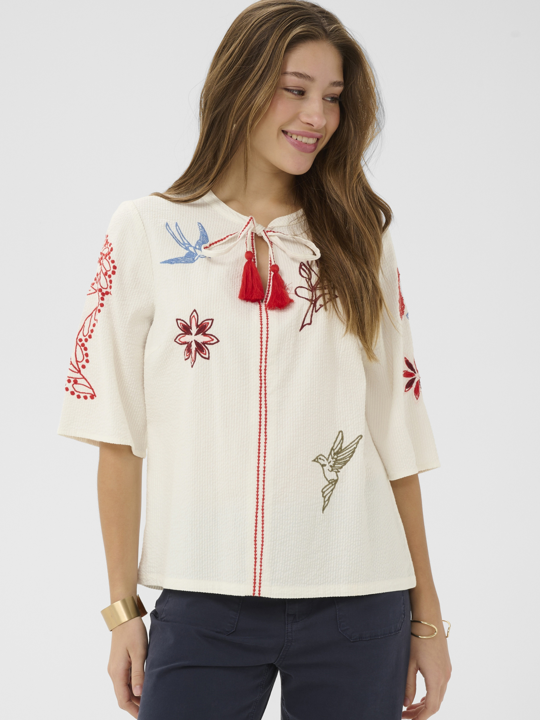 Cream Rosetta Blouse in cotton with multicolour embroidery and tassel tie neckline detail.