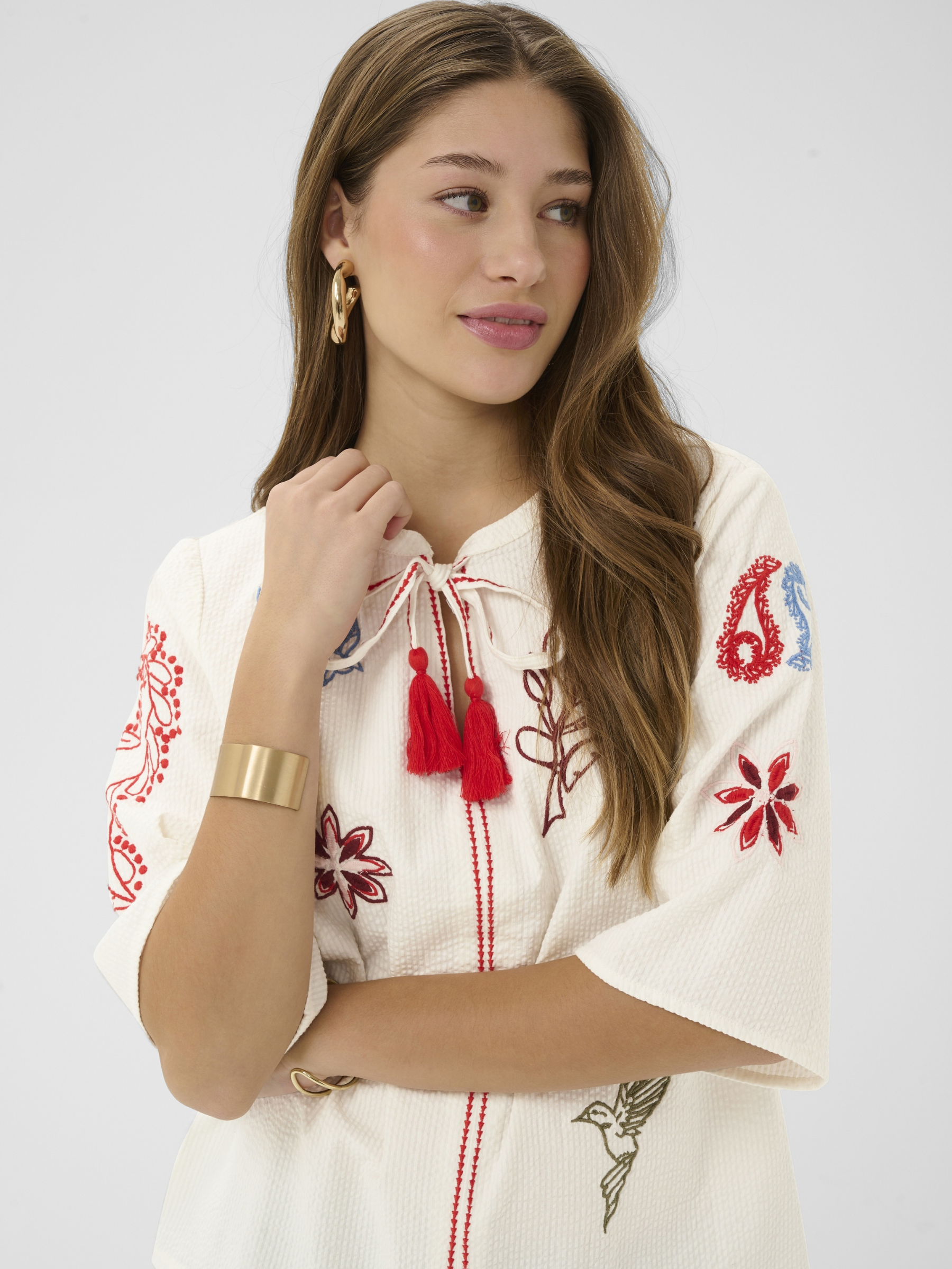 Cream Rosetta Blouse in cotton with multicolour embroidery and tassel tie neckline detail.