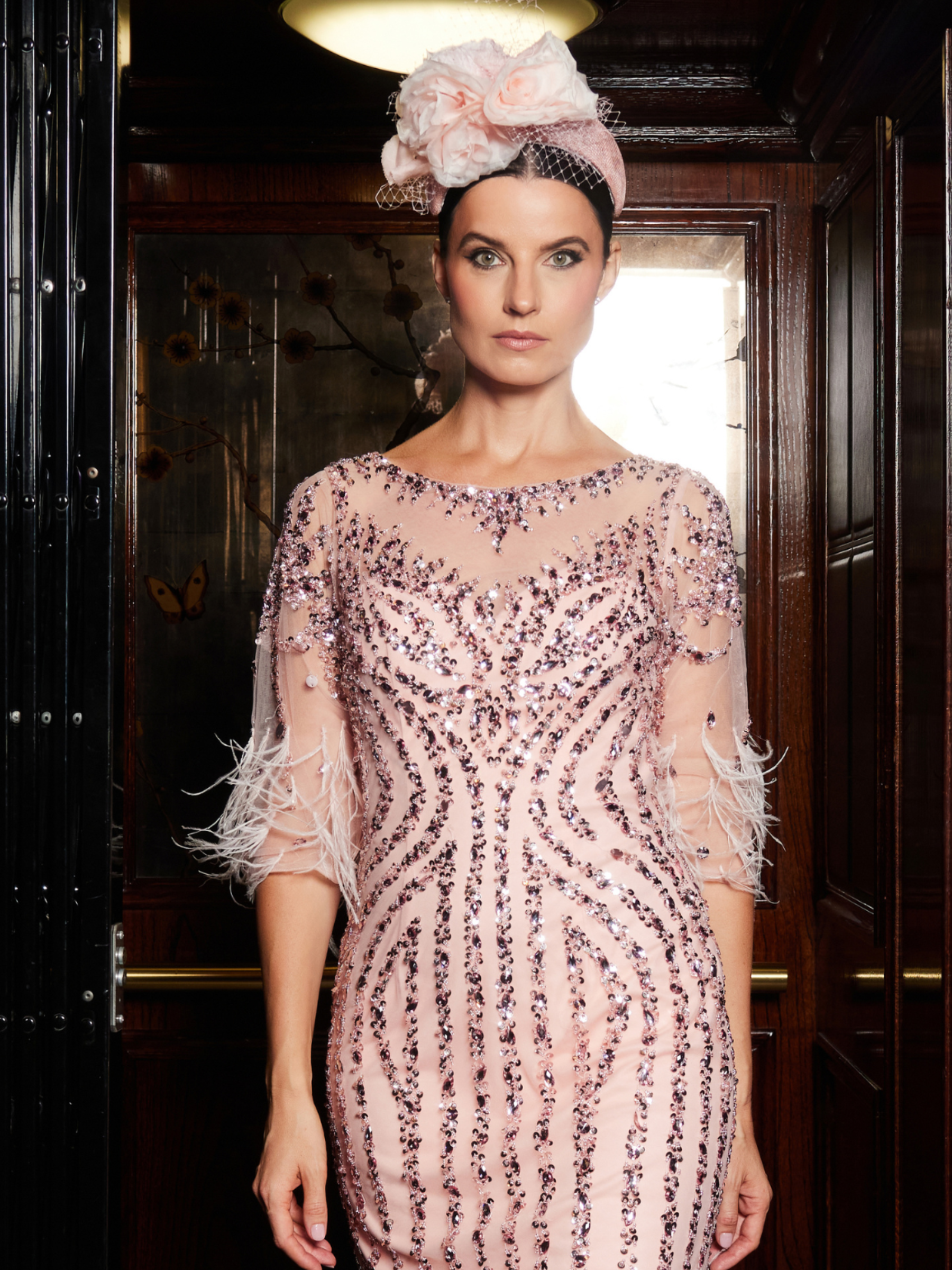 Gill Harvey Champagne Rose Dress featuring sequin embellishment, feather-trimmed sleeves and hemline and a classic boat neckline - a stunning Mother of the Bride or special occasion dress.
