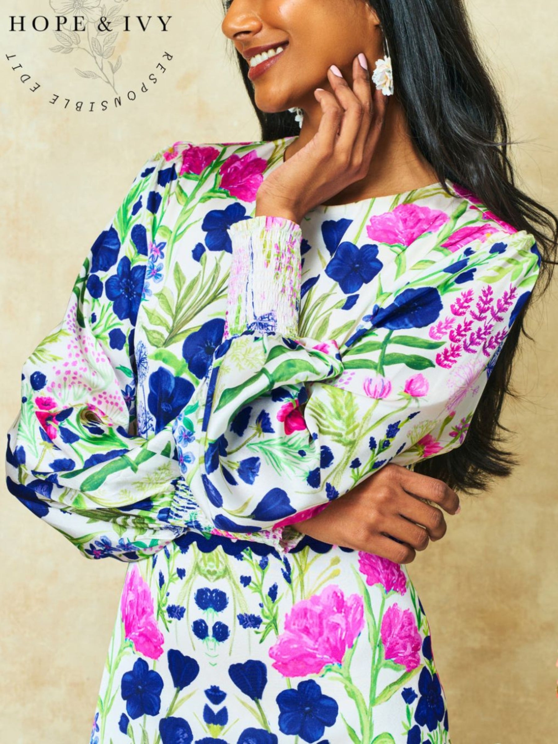 Hope & Ivy Caroline White Floral Maxi Dress – sustainable women’s satin floral print dress with blouson sleeves, frilled hem and tie-back detail. Ideal for weddings, garden parties and summer occasions.