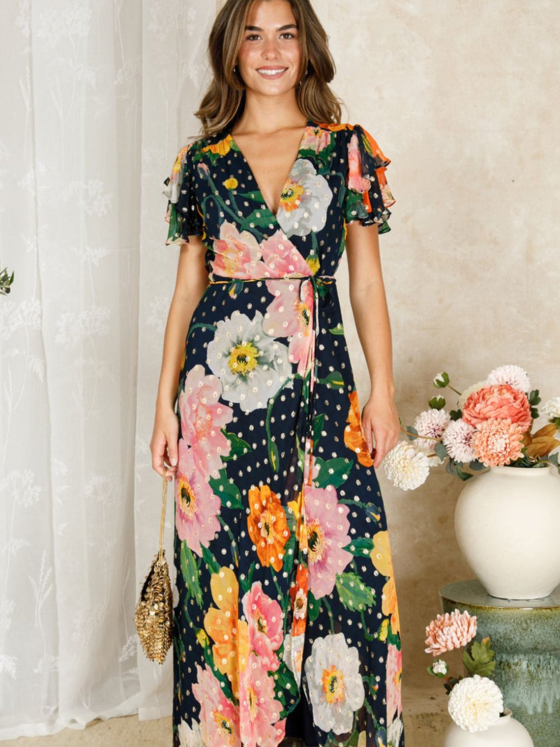 Hope & Ivy Marlene Floral Dress – floral wrap maxi dress with pink, orange and ivory blooms, gold Lurex detail, flutter sleeves and tie waist. Perfect for weddings, garden parties and summer events.