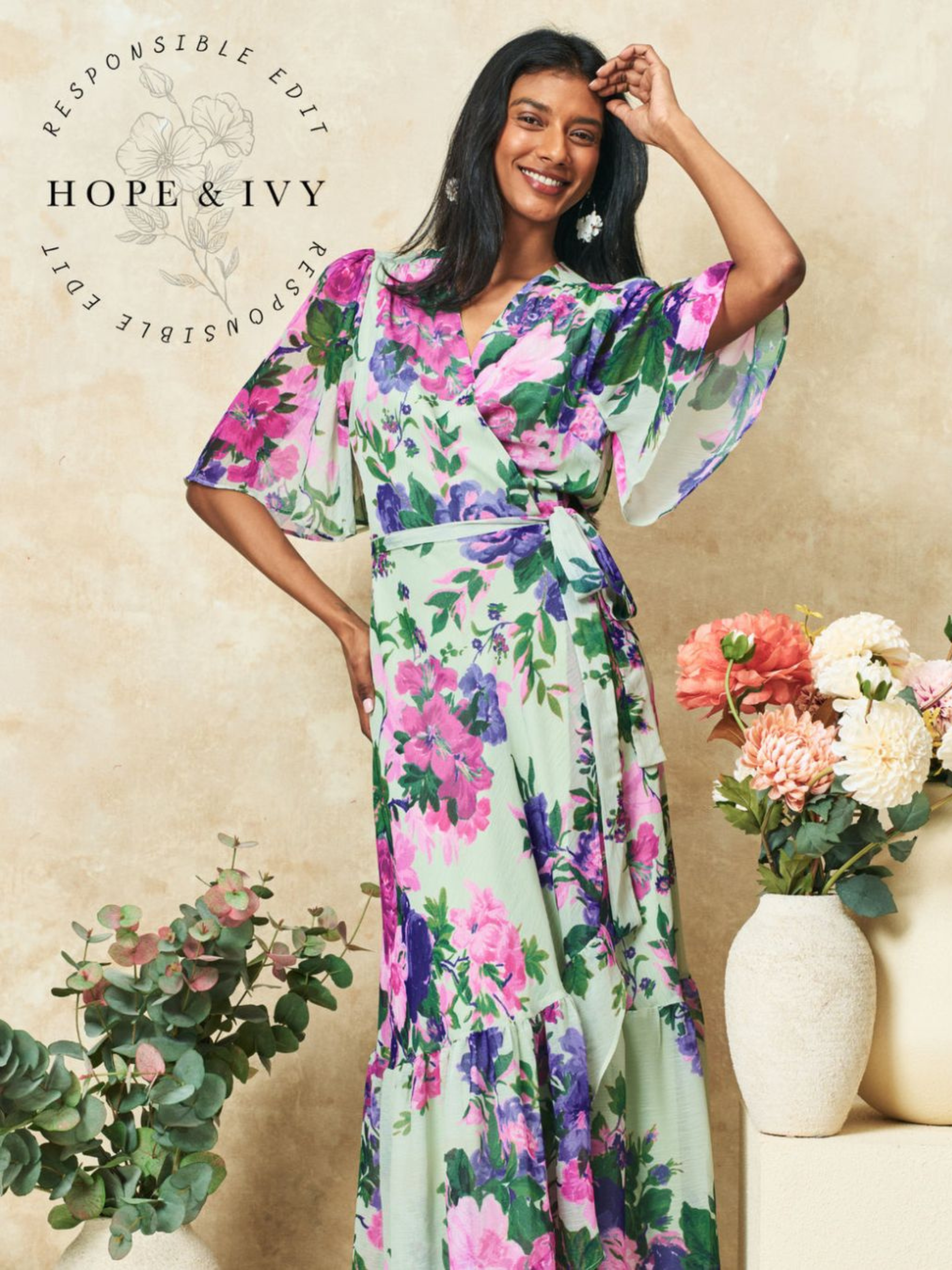Hope & Ivy Priscilla Floral Dress – sustainable sage-green floral maxi wrap dress with flutter sleeves and tie waist. Made from 100% recycled materials. Perfect for weddings and summer occasions.