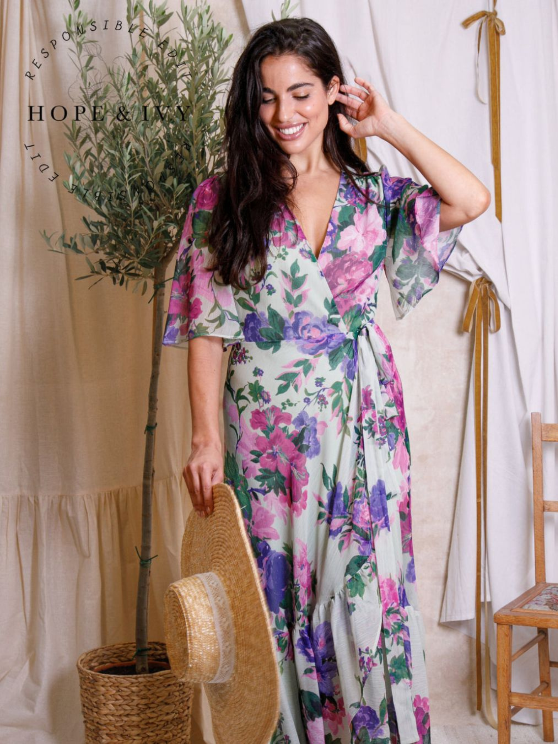 Hope & Ivy Priscilla Floral Dress – sustainable sage-green floral maxi wrap dress with flutter sleeves and tie waist. Made from 100% recycled materials. Perfect for weddings and summer occasions.