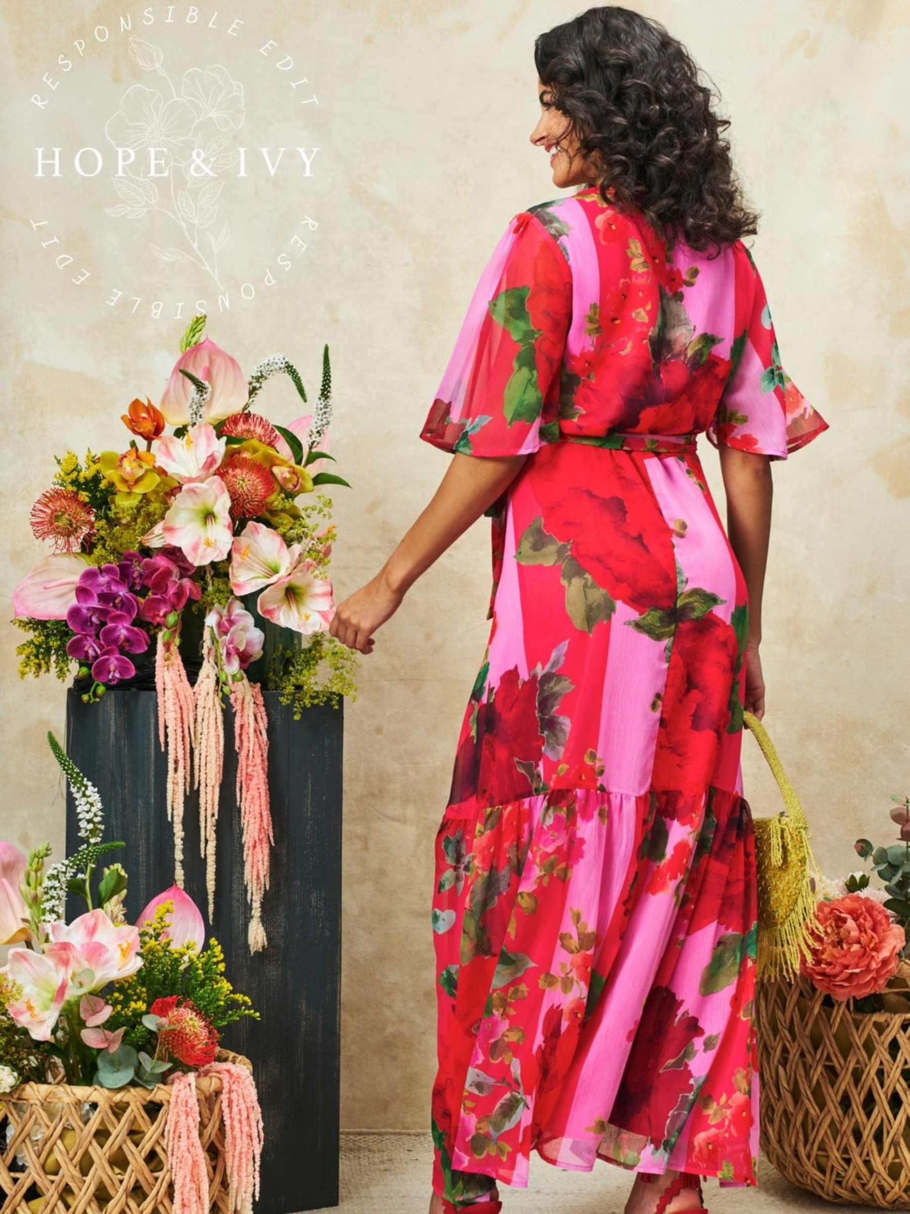 Hope & Ivy Rosanna Pink & Red Dress with wrap-style silhouette, V-neckline, flutter sleeves, tie waist and flowing maxi skirt with front split.