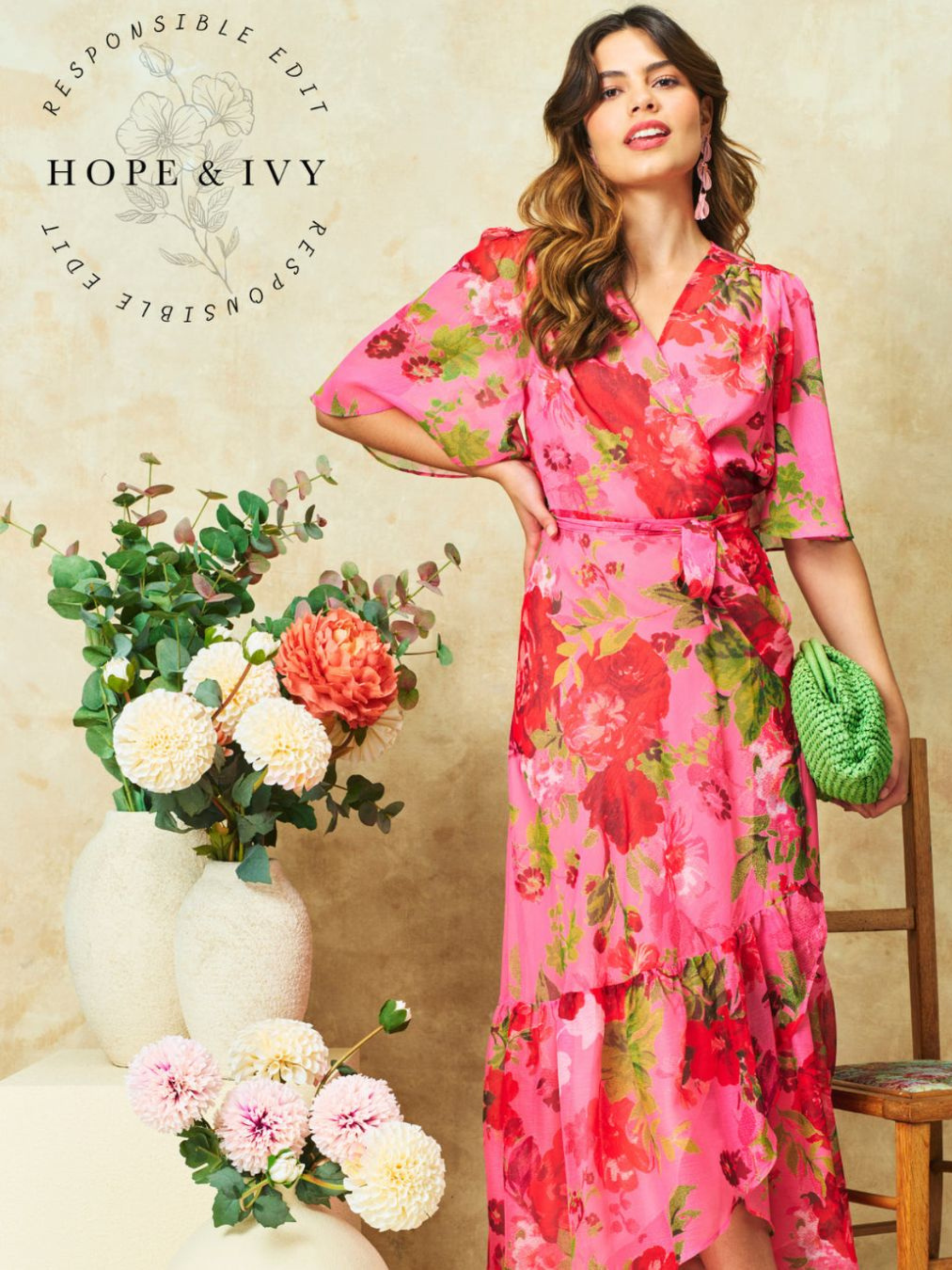 Hope & Ivy Roxanne Floral Dress – sustainable pink floral maxi wrap dress with flutter sleeves and tie waist. Hand-painted red floral design made from 100% recycled materials. Perfect for weddings and summer occasions.