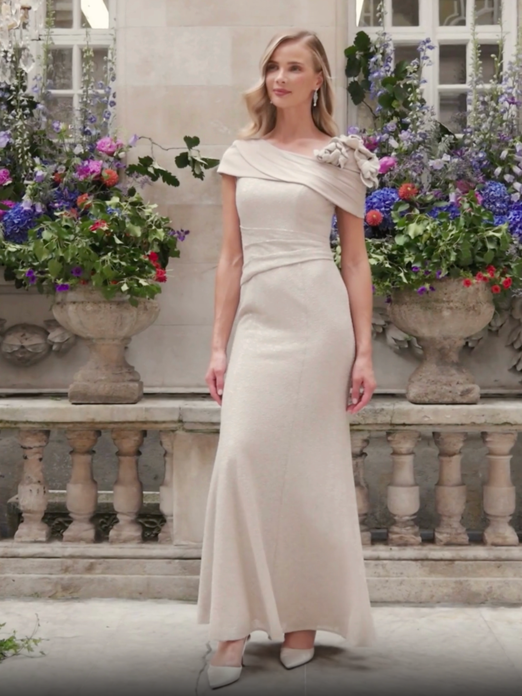 John Charles 29337B Oyster Dress with asymmetric bardot collar, sparkle stretch fabric, long straight skirt and floral shoulder detailing.