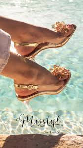 A pair of gold-colored flat sandals with ankle straps, displayed in a manner that suggests they are being worn by a person sitting by a poolside.