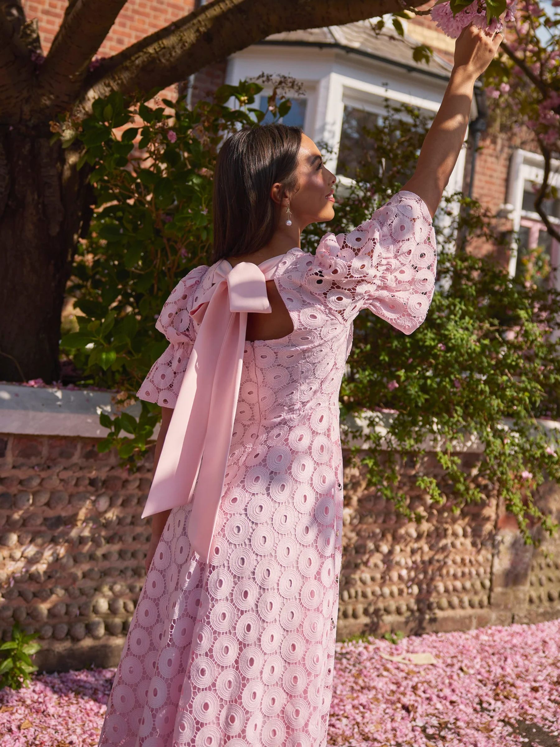 Pale pink skater midi dress with broderie-style fabric, puff sleeves and bow back detail.