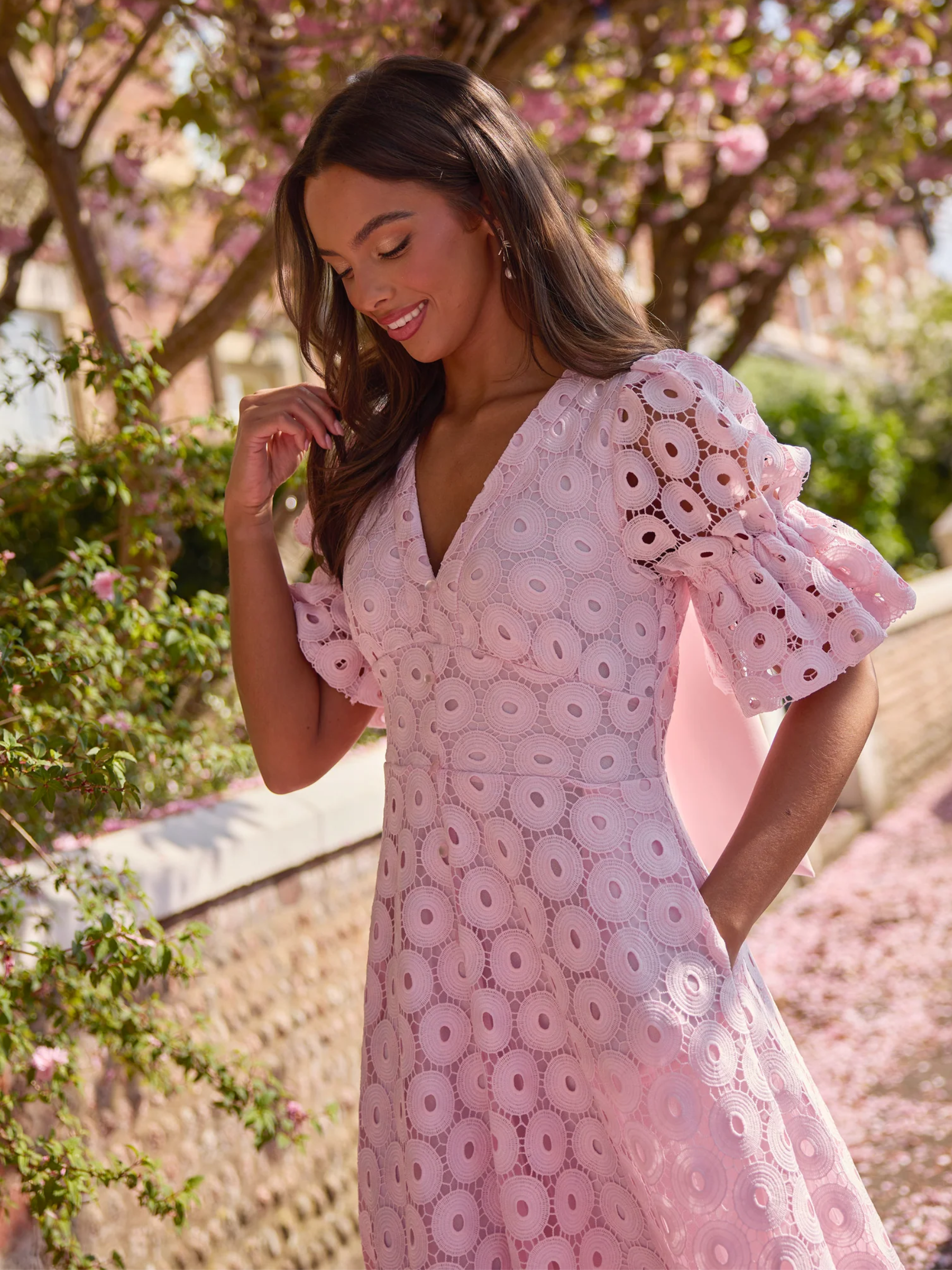 Pale pink skater midi dress with broderie-style fabric, puff sleeves and bow back detail.