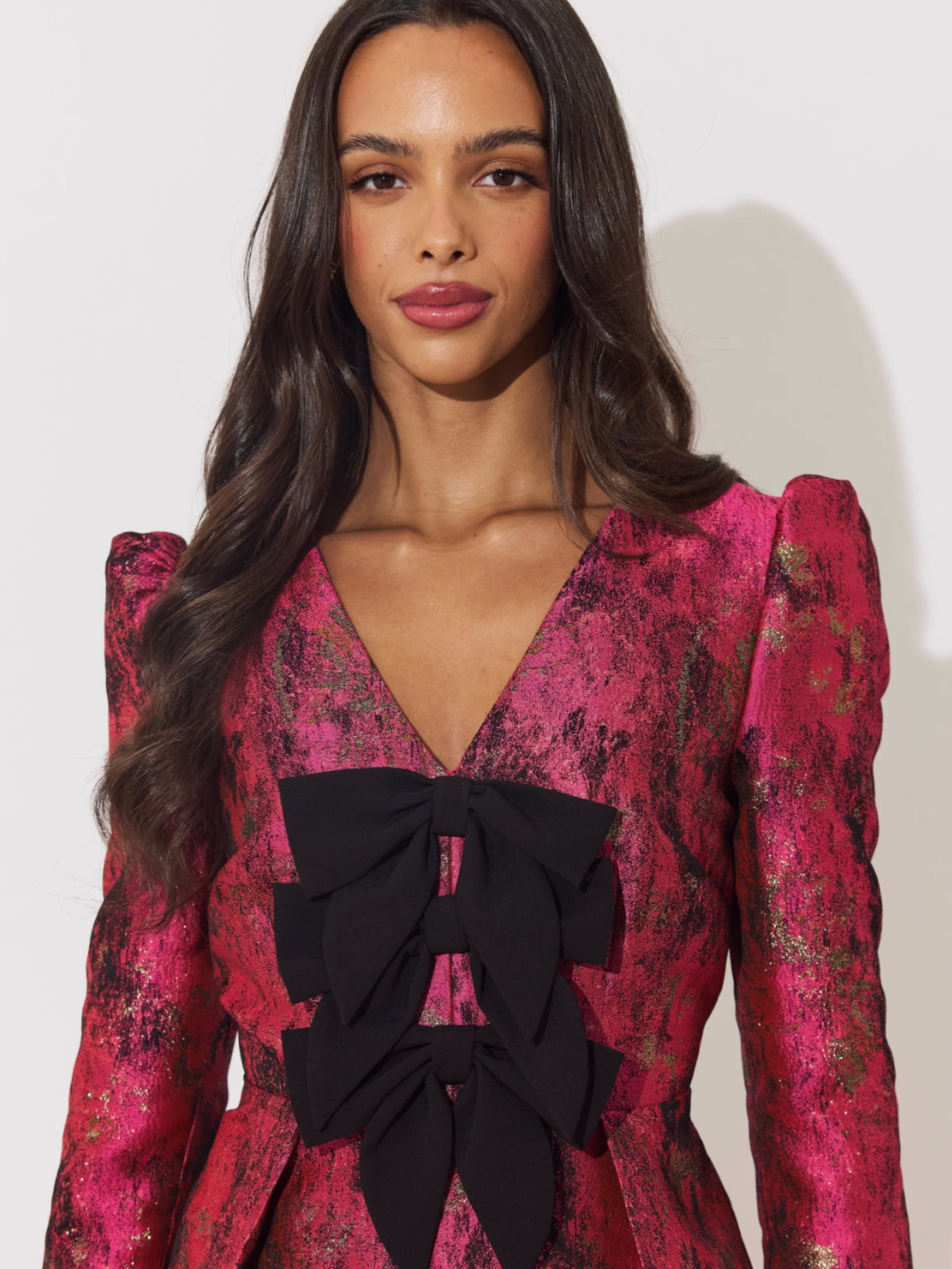The 8th Sign Veronica Metallic Mini Dress with deep V neckline, statement bow detailing, puff shoulders and A-line skirt.