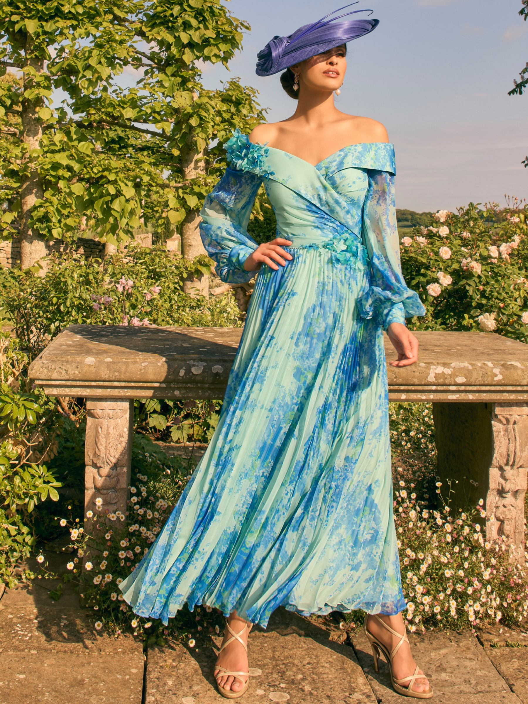 Veni Infantino 992780 Ocean Print Dress – off-the-shoulder chiffon print occasion dress with sheer bishop sleeves, pleated skirt and 3D floral appliqué waistband for weddings and race days.