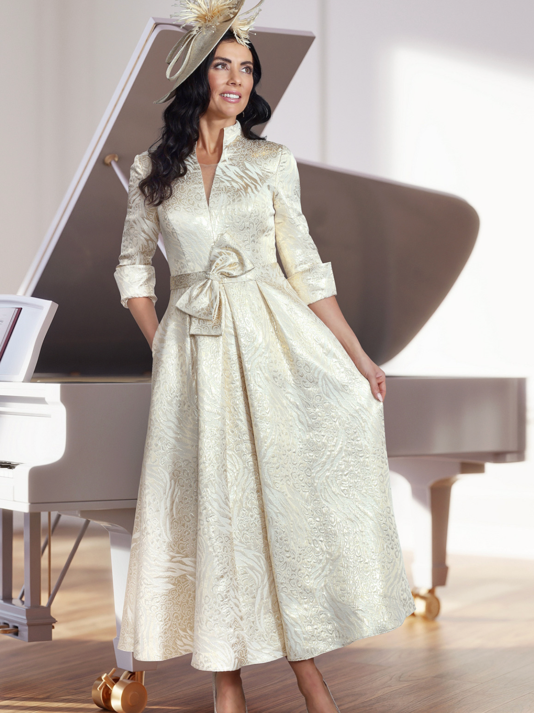 Veromia Occasions VO2906 gold jacquard midi dress with V-neckline, three-quarter sleeves, bow waist detail and A-line skirt.