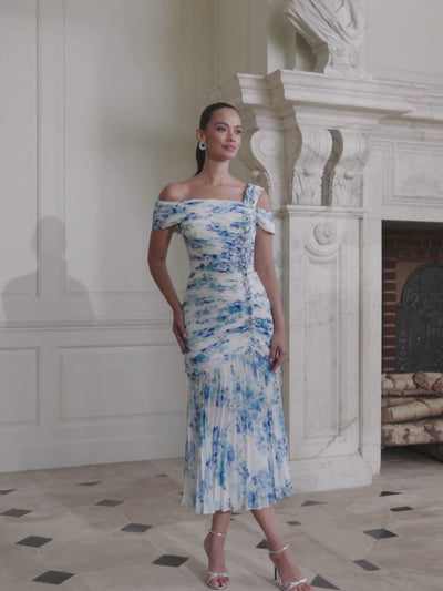 John Charles 66727A Blue Blossom Dress with off-the-shoulder wrap neckline, asymmetric strap detail, ruched bodice and pleated full-length chiffon skirt — a romantic floral occasion dress perfect for weddings and elegant events.