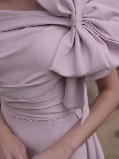 Veni Infantino 992731 Lilac crepe dress with off-the-shoulder neckline, oversized bow and flared A-line skirt. Elegant occasion dress for weddings and special events.
